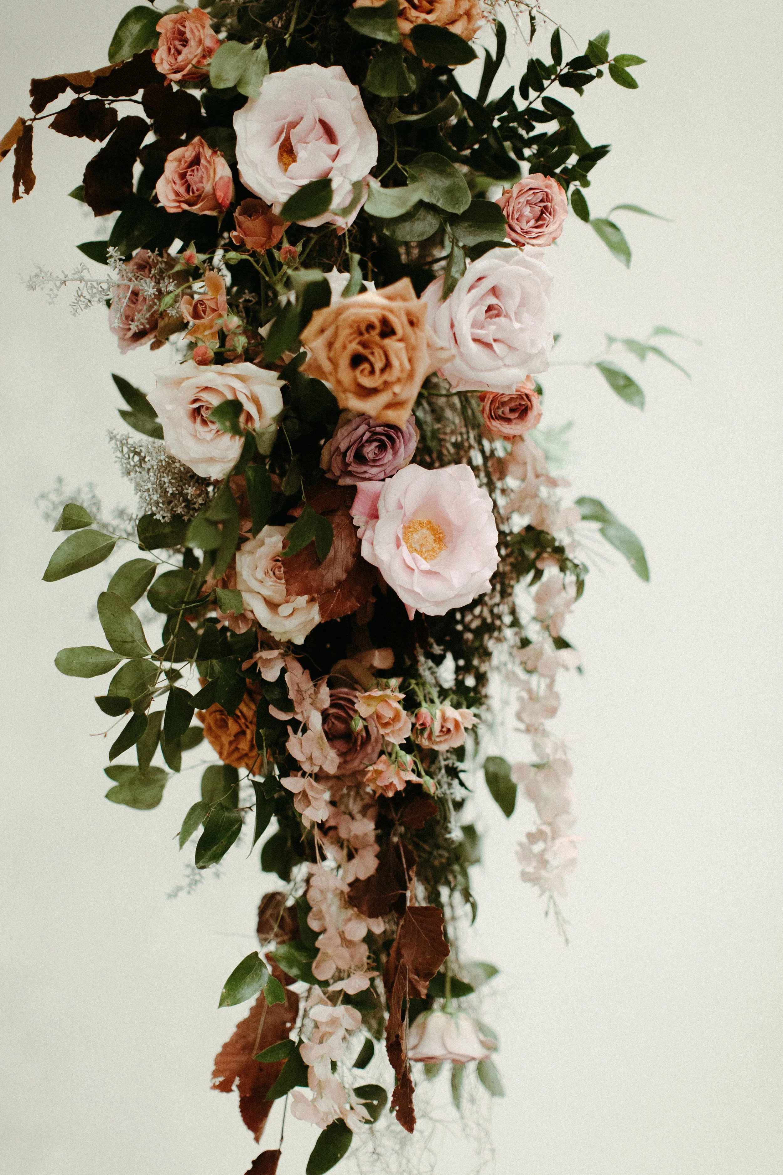 An eye-catching whimsical installation full of petal heavy roses and copper beech was the highlight of this art deco wedding. Terra cotta, burgundy, dusty pink, and other neutral florals warm up this ceremony. Designed by Rosemary and Finch in Nashvi
