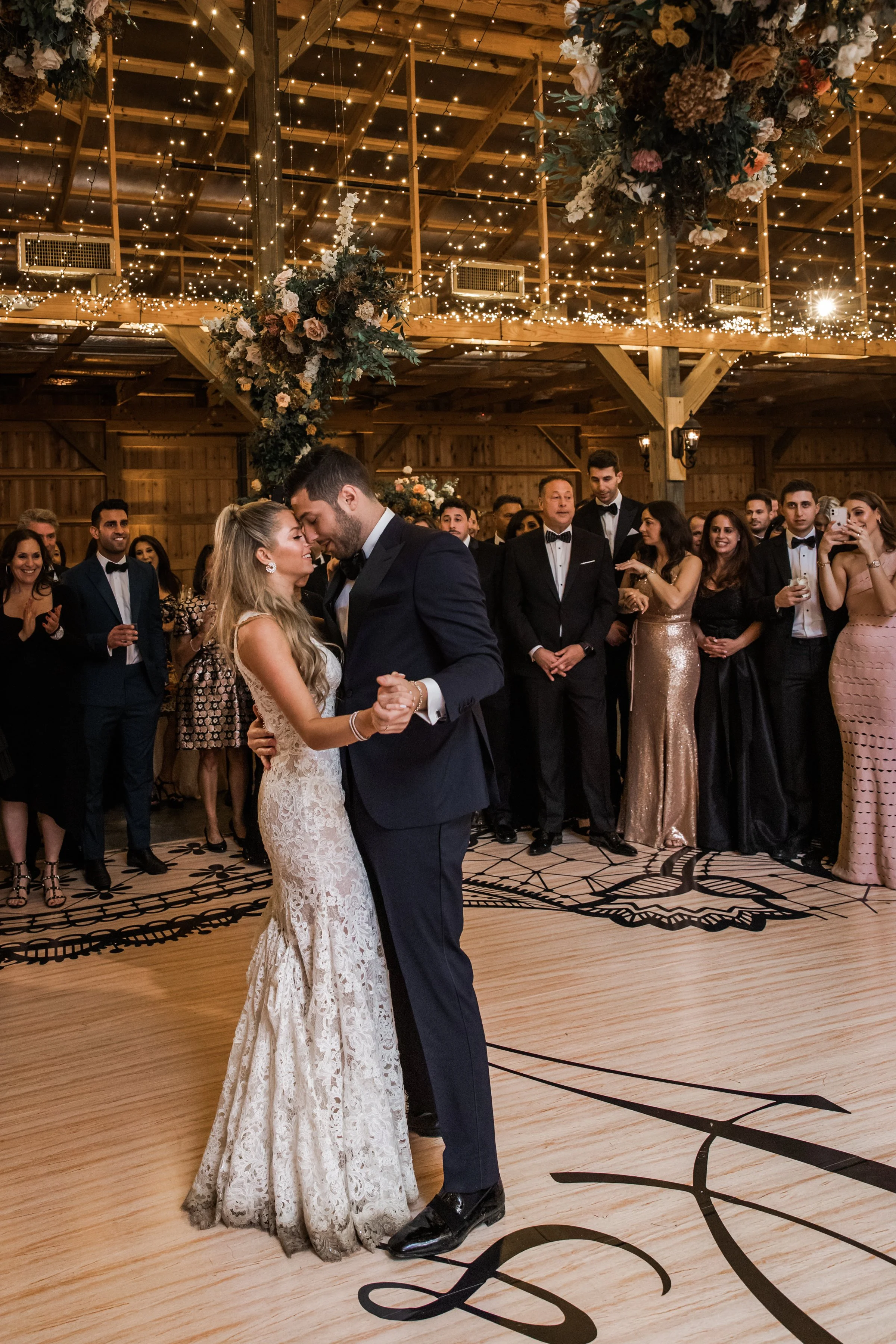 Gorgeous autumnal floral clouds hang over the dance floor, including terra cotta, rose gold, toffee, blush, and neutral florals. These clouds feature lush garden roses, ranunculus, lisianthus, and privet berries. Designed by Rosemary and Finch in Nas