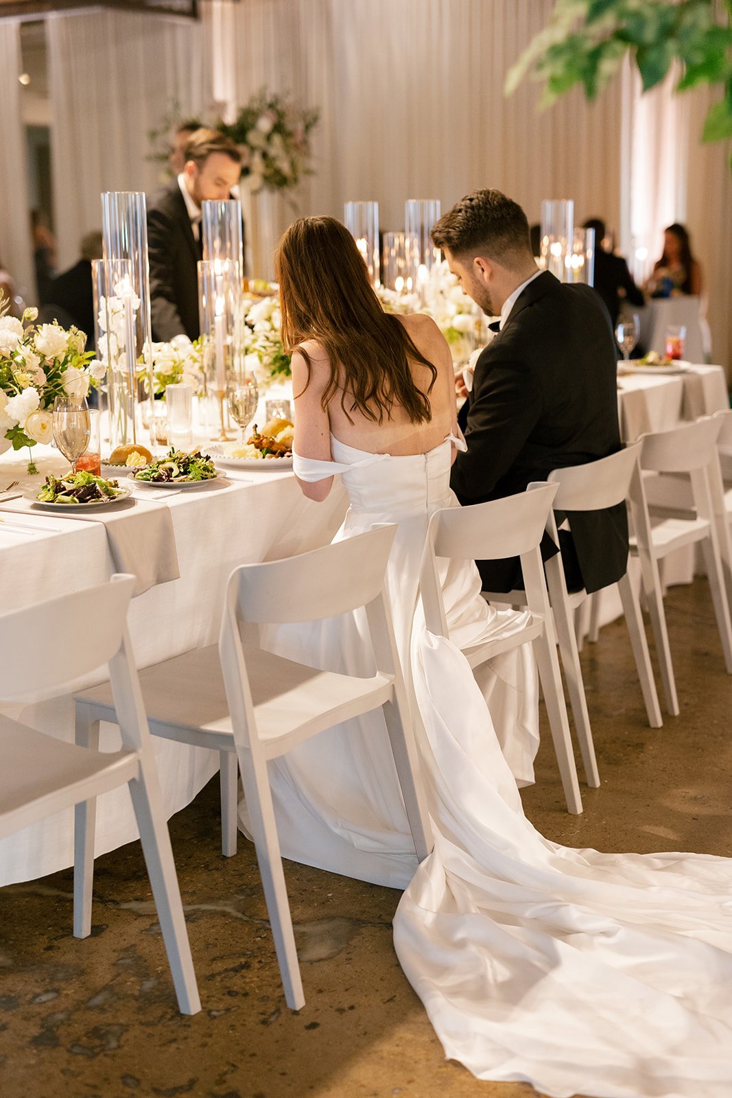 Low floral centerpieces for elegant wedding overflowing with white garden roses, ranunculus, butterfly ranunculus, scabiosa, lisianthus, sweet peas, and natural dark greenery. Floral hues of white, cream, and blush. Designed by Rosemary and Finch in
