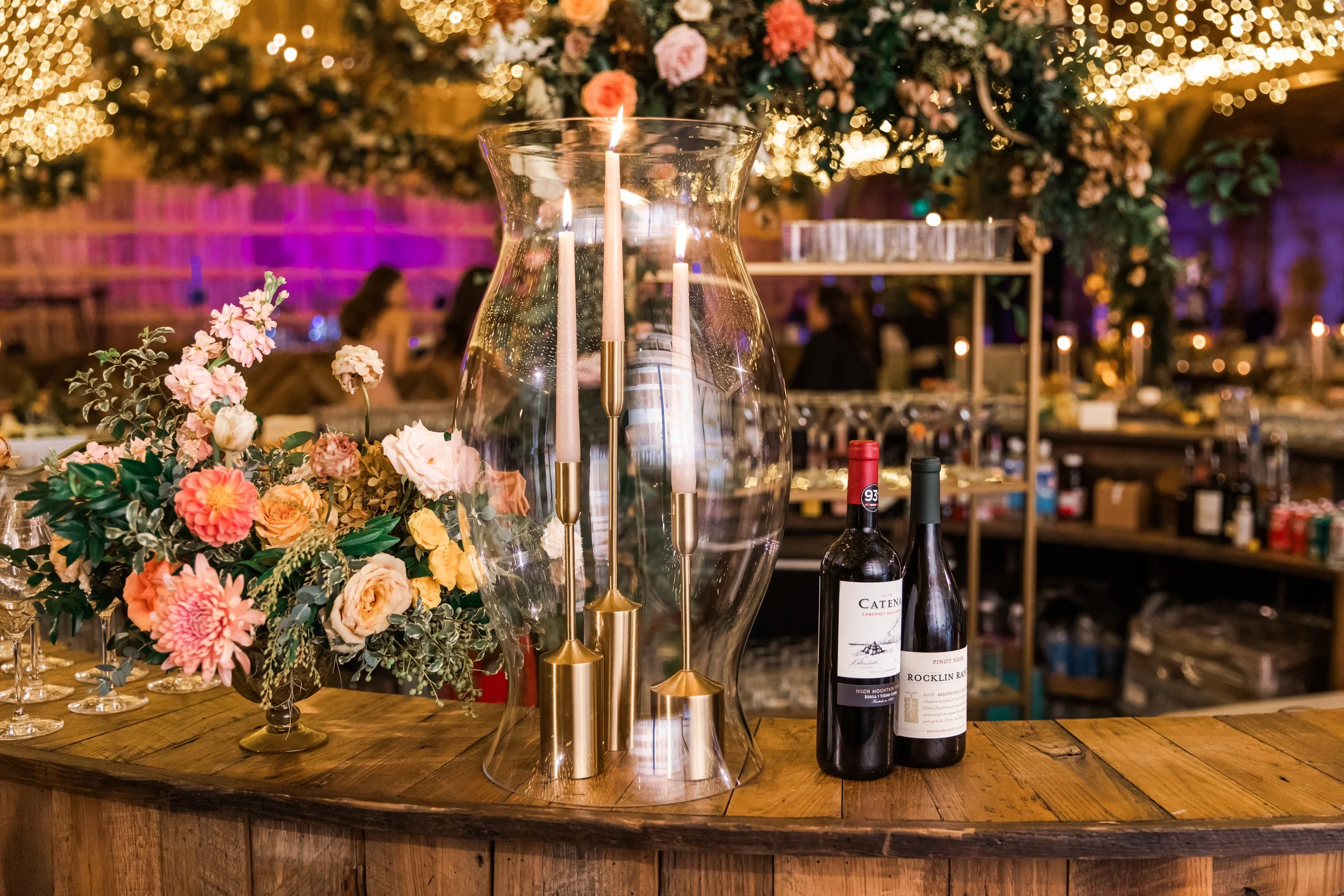 Beautiful fall floral centerpieces warm this reception space with a sunset color palette. Garden roses, ranunculus, double brownie tulips, and lisianthus create hues of terra cotta, blush pink, copper, and yellow. Designed by Rosemary and Finch in Na
