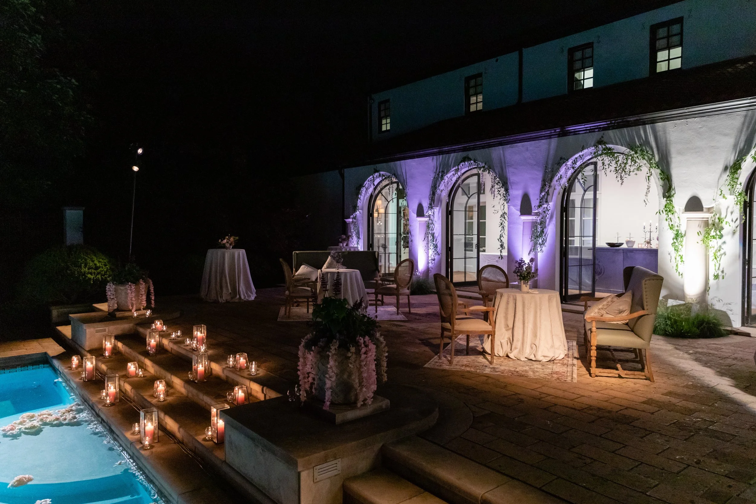 Bridgerton inspired engagement party at a private home in Nashville, TN with pastel candles and flowers floating in the pool with wisteria and delphinium growing over the bar. Nashville wedding floral designer, Rosemary & Finch.