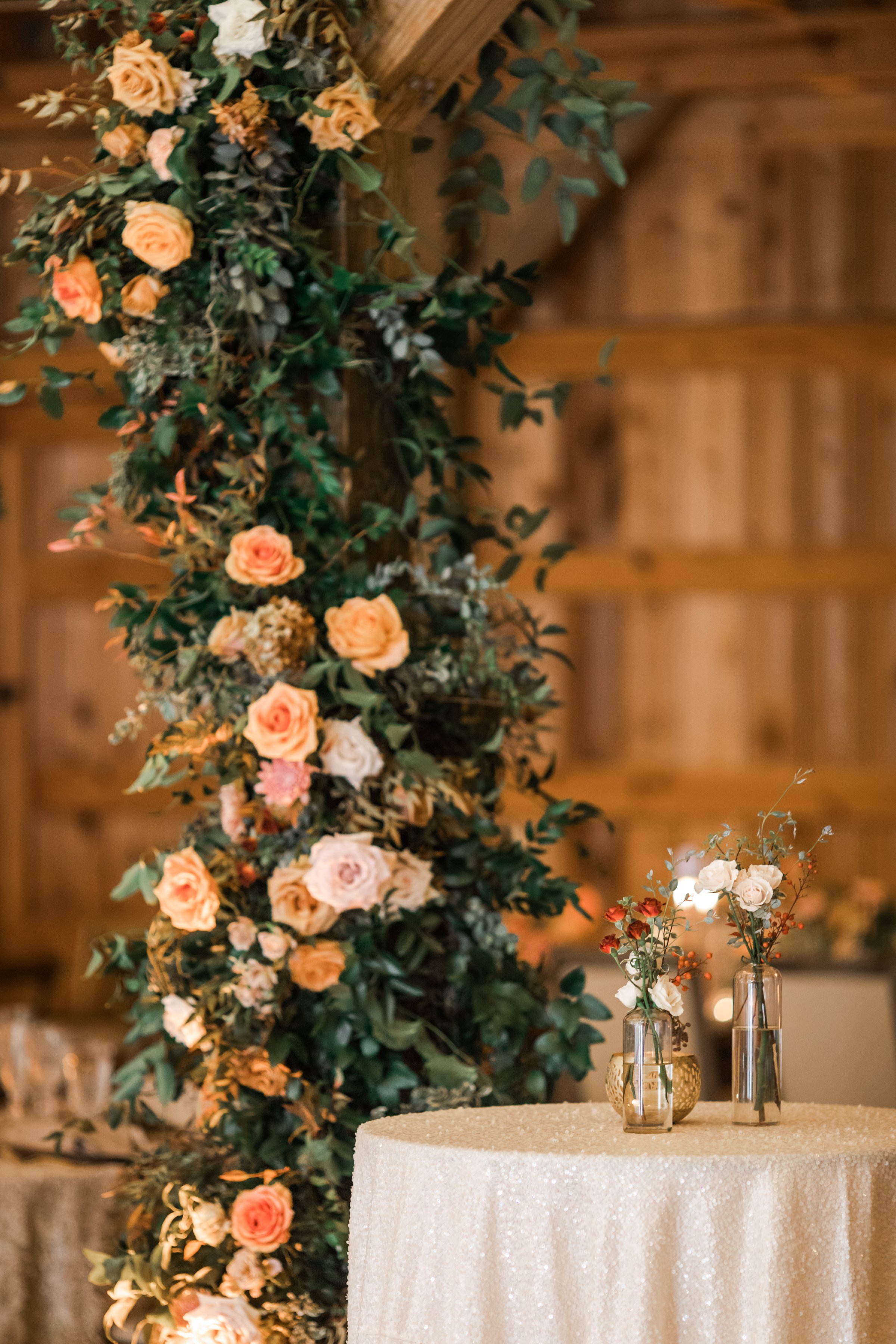 Climbing barn pole floral installations add pops of terra cotta, blush pink, and copper hues throughout the reception. Fall florals featuring garden roses and dahlias. Designed by Rosemary and Finch in Nashville, TN.