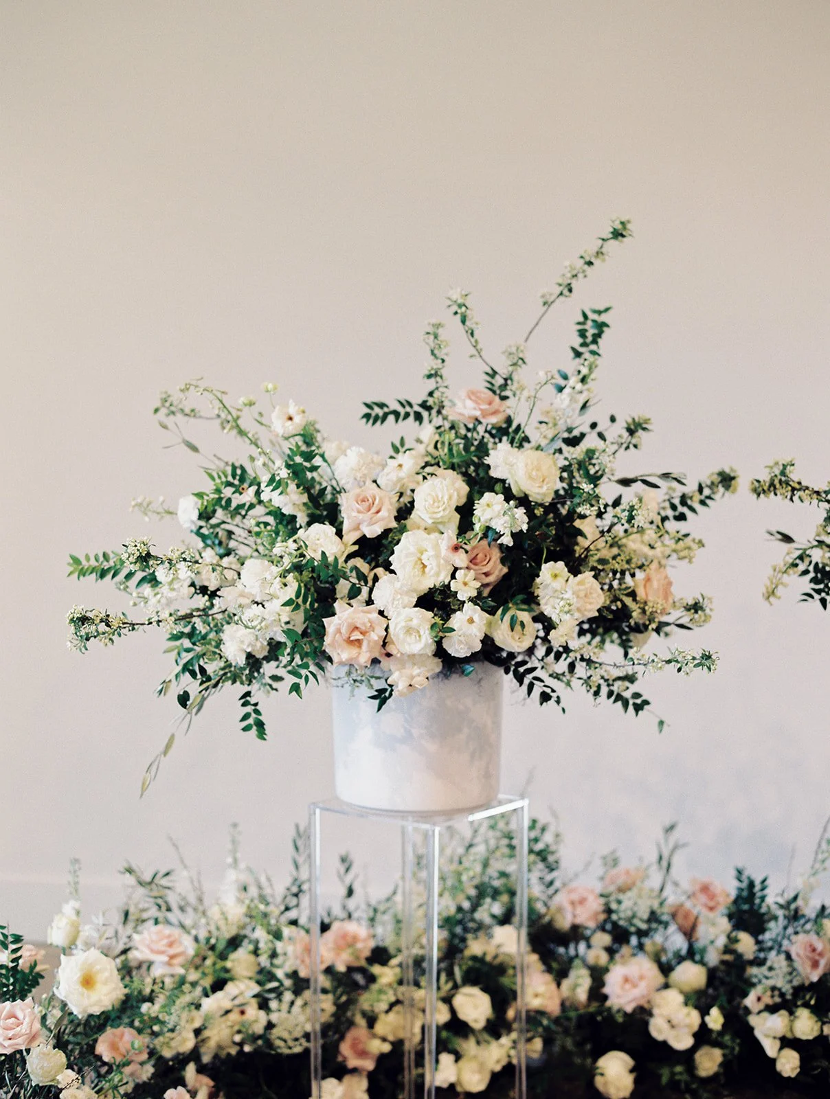 Lush ceremony installation featuring garden urns and meadows with petal heavy roses butterfly ranunculus, delphinium, and Queen Anne’s lace with natural, untamed greenery. Floral hues of white, cream, and blush. Designed by Rosemary and Finch in Nash