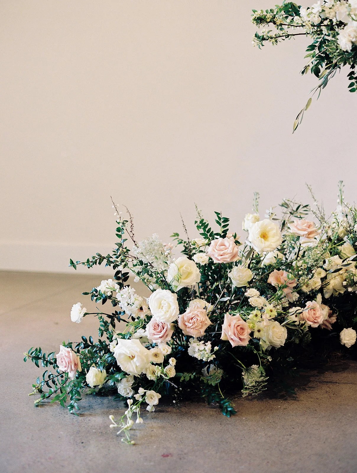 Lush ceremony installation featuring garden urns and meadows with petal heavy roses butterfly ranunculus, delphinium, and Queen Anne’s lace with natural, untamed greenery. Floral hues of white, cream, and blush. Designed by Rosemary and Finch in Nash