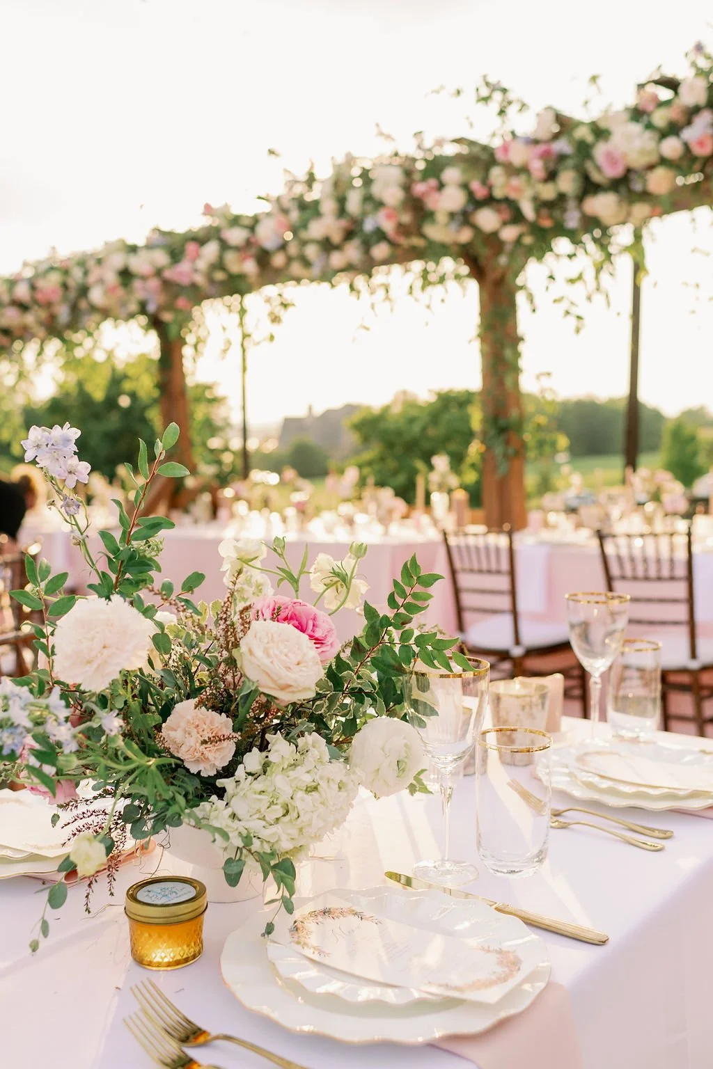 This garden-inspired reception features floral hues of blush, ivory, cream, pink, and hints of French blue along with centerpieces of pink roses, peonies, garden roses, blue delphinium, ranunculus, spirea and hydrangea. Designed by Rosemary & Finch i