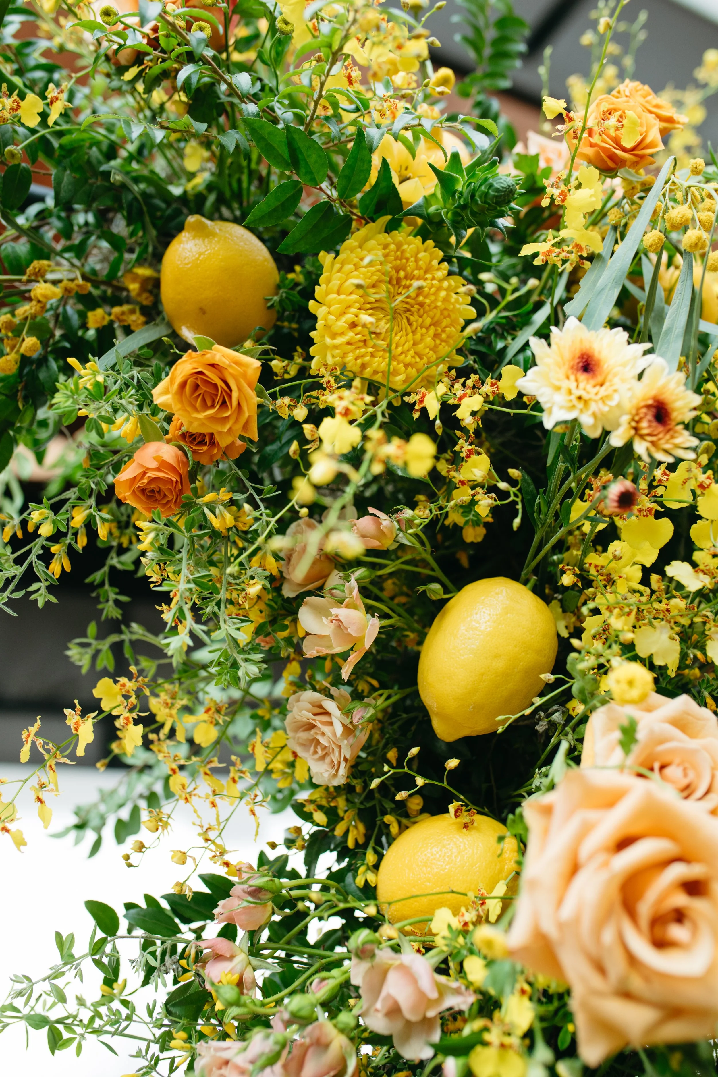 Bold spring floral installation of yellow and green hues comprised of roses, mums, orchids, tulips, carnations, mixed greenery, and lemons! Designed by Rosemary and Finch for Fifth + Broadway event in Downtown Nashville, TN.