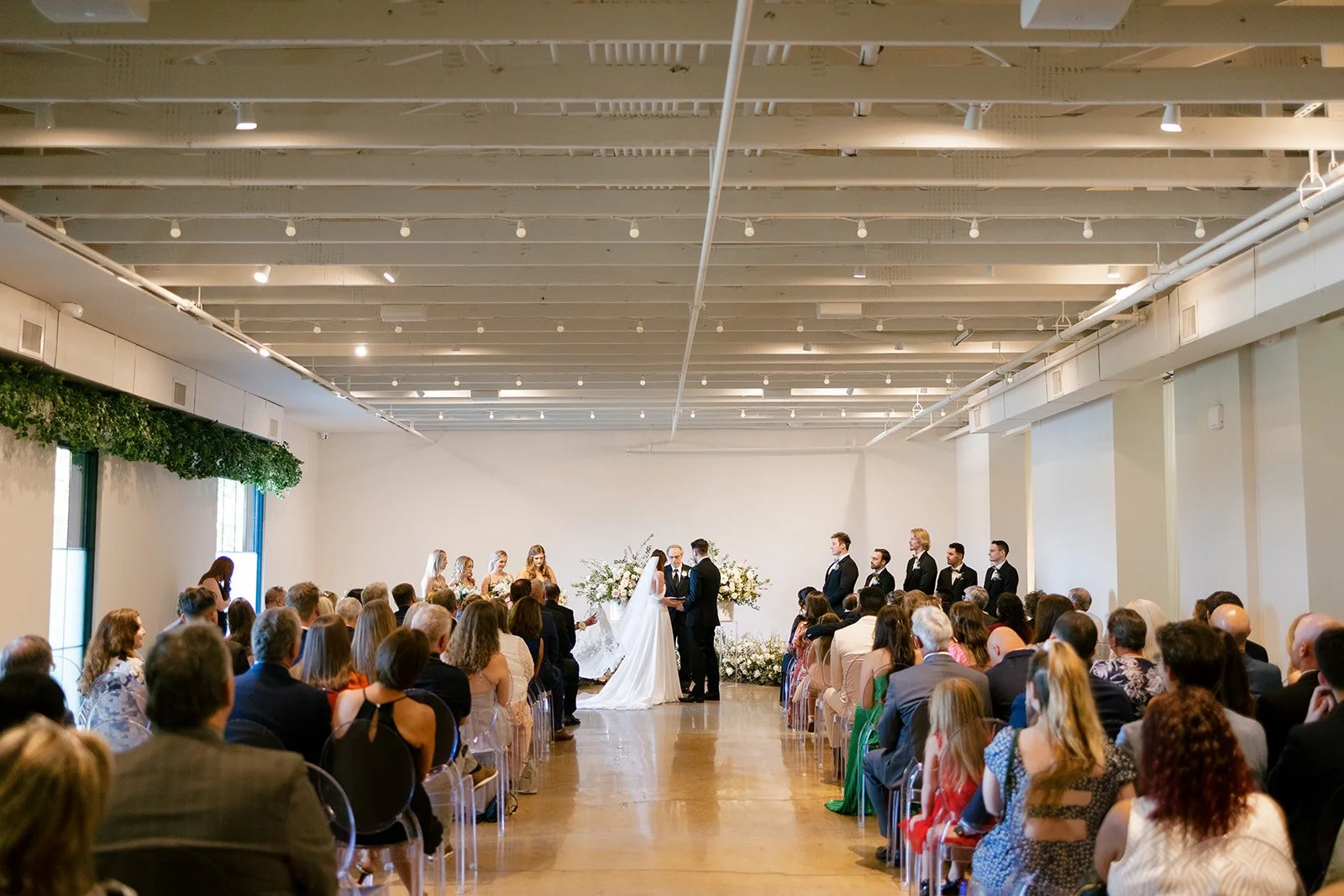 Lush ceremony installation featuring garden urns and meadows with petal heavy roses butterfly ranunculus, delphinium, and Queen Anne’s lace with natural, untamed greenery. Floral hues of white, cream, and blush. Designed by Rosemary and Finch in Nash