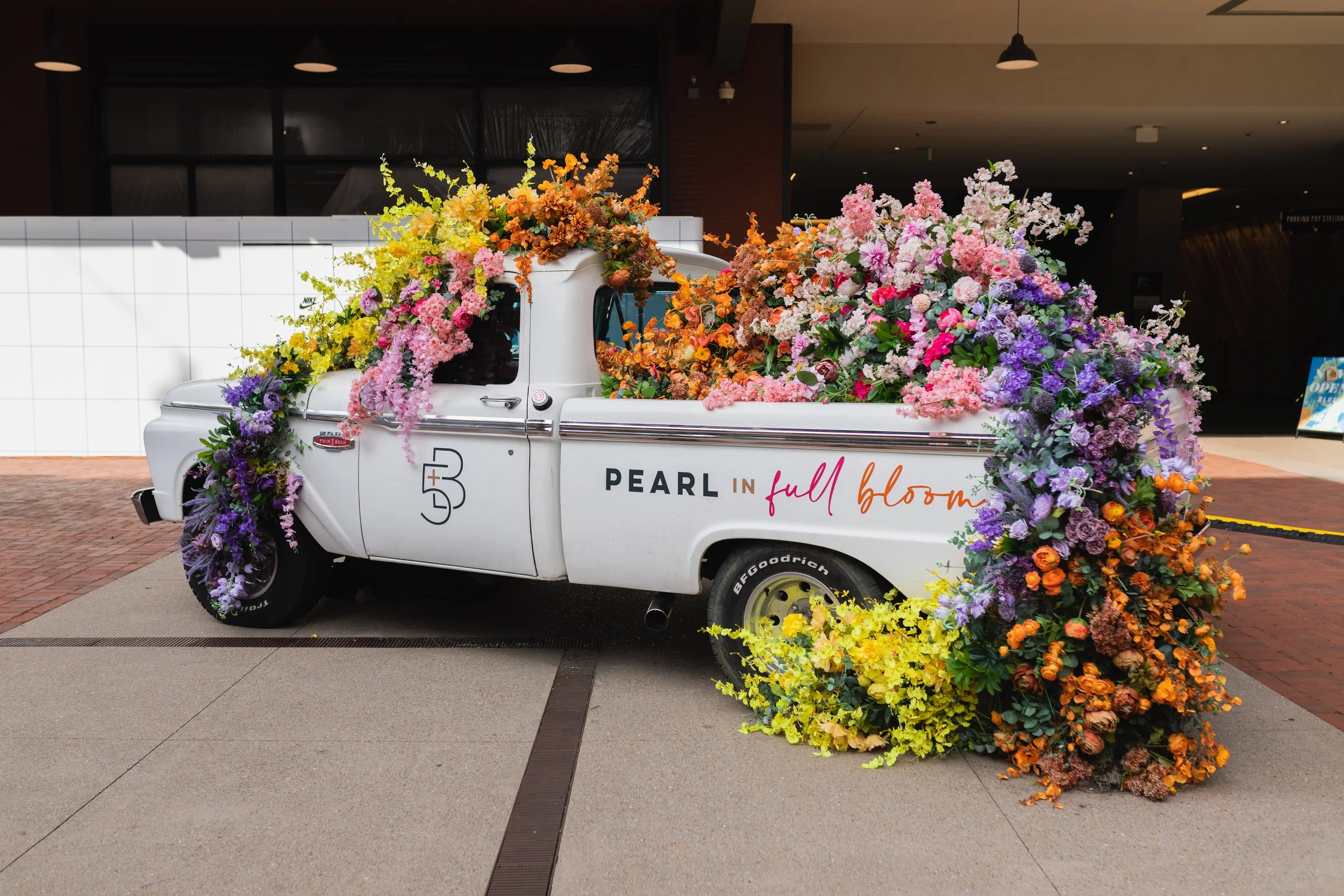 Cheerful pickup truck installation composed of silk floral hues in pink, magenta, lavender, coral, orange, yellow, and mixed greens bring to life this spring Fifth + Broadway event in Nashville, TN. Design by Rosemary and Finch.