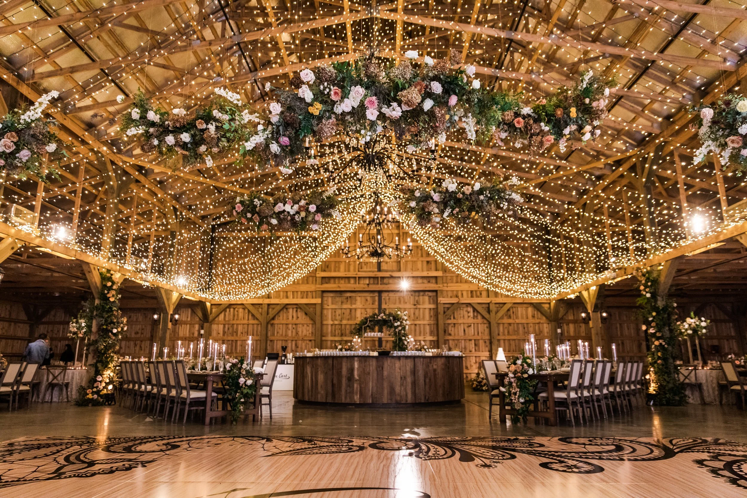 Gorgeous autumnal floral clouds hang over the dance floor, including terra cotta, rose gold, toffee, blush, and neutral florals. These clouds feature lush garden roses, ranunculus, lisianthus, and privet berries. Designed by Rosemary and Finch in Nas