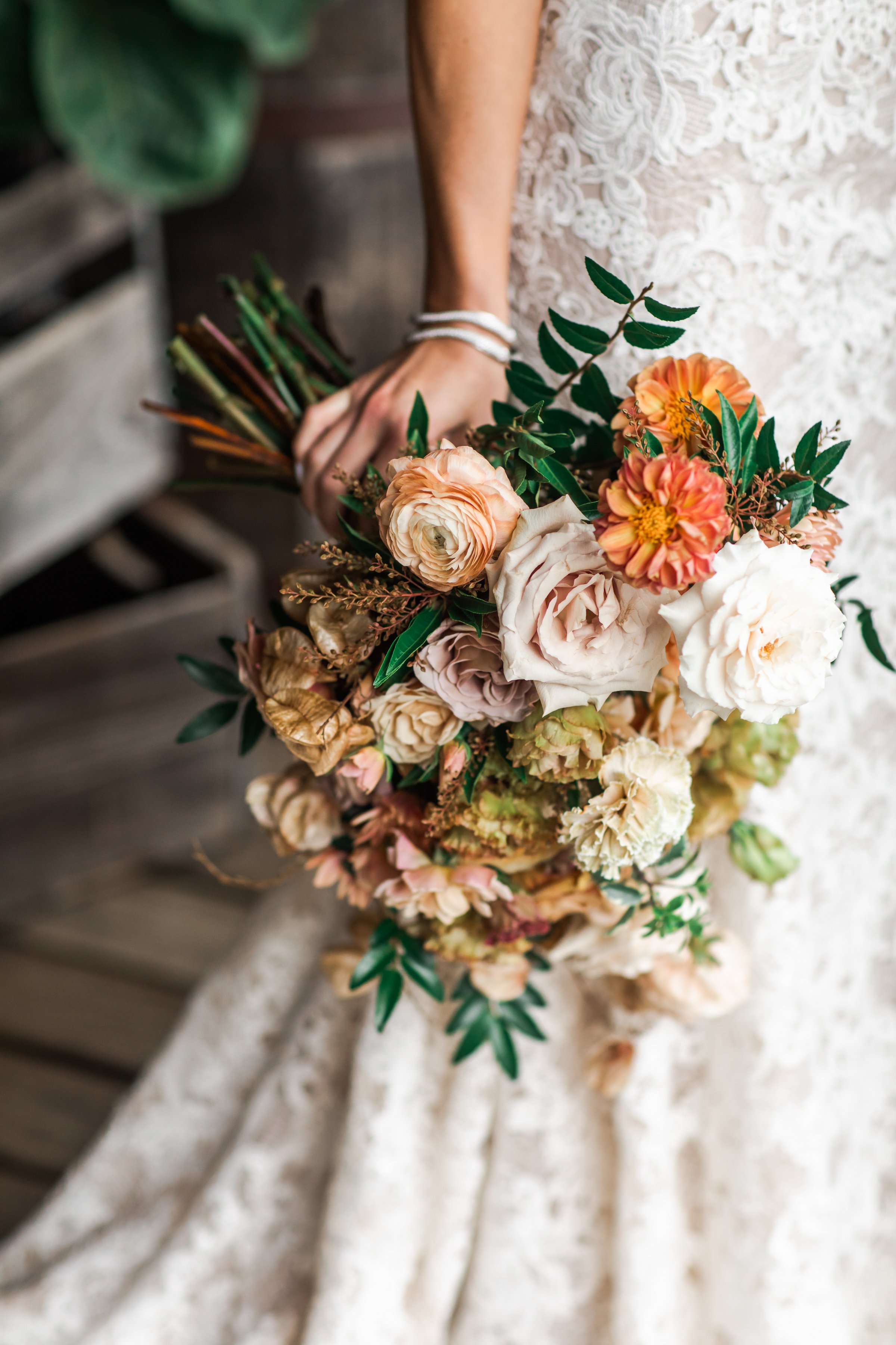 An elegant fall bridal bouquet featuring a sunset color palette of blush, terra cotta, rose gold, yellow, and copper. Florals accents of dahlias, garden roses, ranunculus, and double brownie tulips. Designed by Rosemary and Finch in Nashville, TN.
