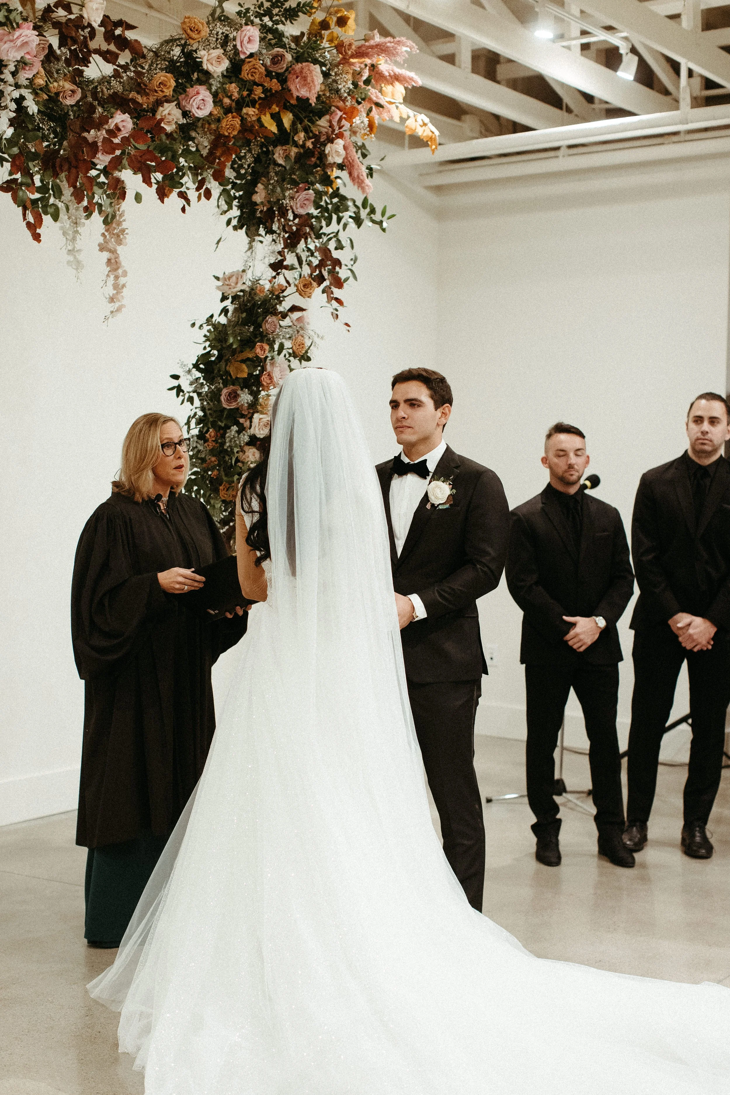 An eye-catching whimsical installation full of petal heavy roses and copper beech was the highlight of this art deco wedding. Terra cotta, burgundy, dusty pink, and other neutral florals warm up this ceremony. Designed by Rosemary and Finch in Nashvi