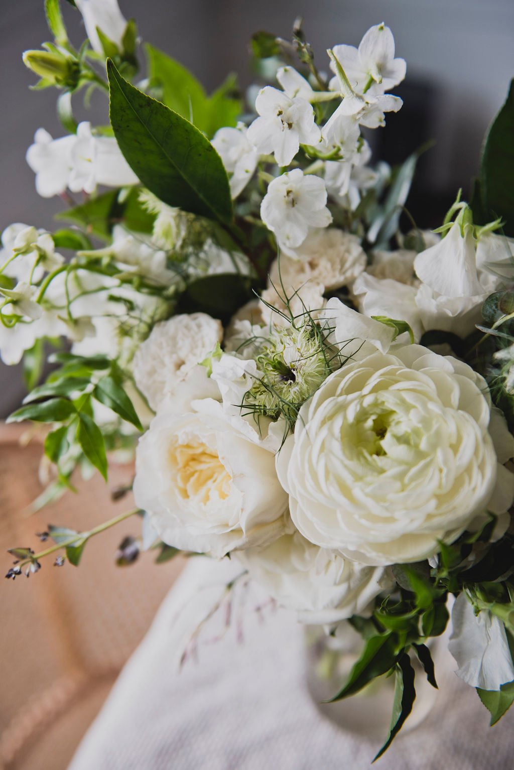 A bridal bouquet filled with ranunculus, delphinium, white sweet pea, spirea, garden roses, and jasmine vine. Designed by Rosemary and Finch in Nashville, TN.