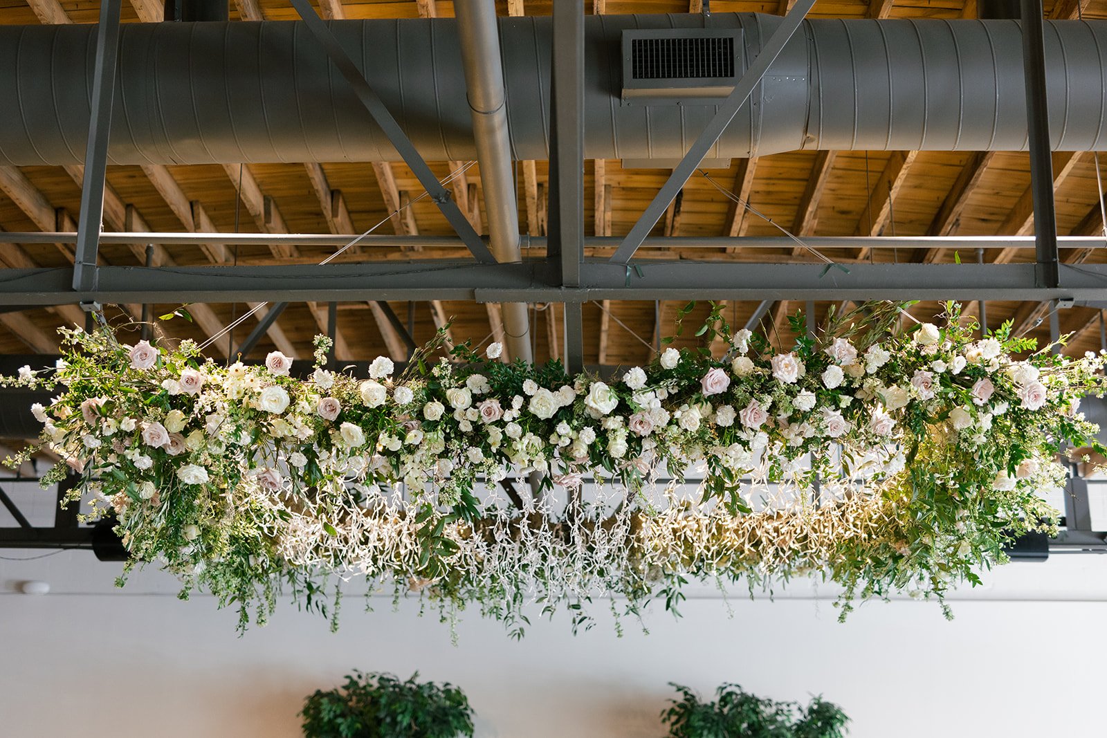 Lush floral chandelier lights up the dance floor with florals of petal heavy roses, ranunculus, lisianthus, delphinium, and dark greenery in hues of white, cream, and blush. Designed by Rosemary and Finch in Nashville, TN.