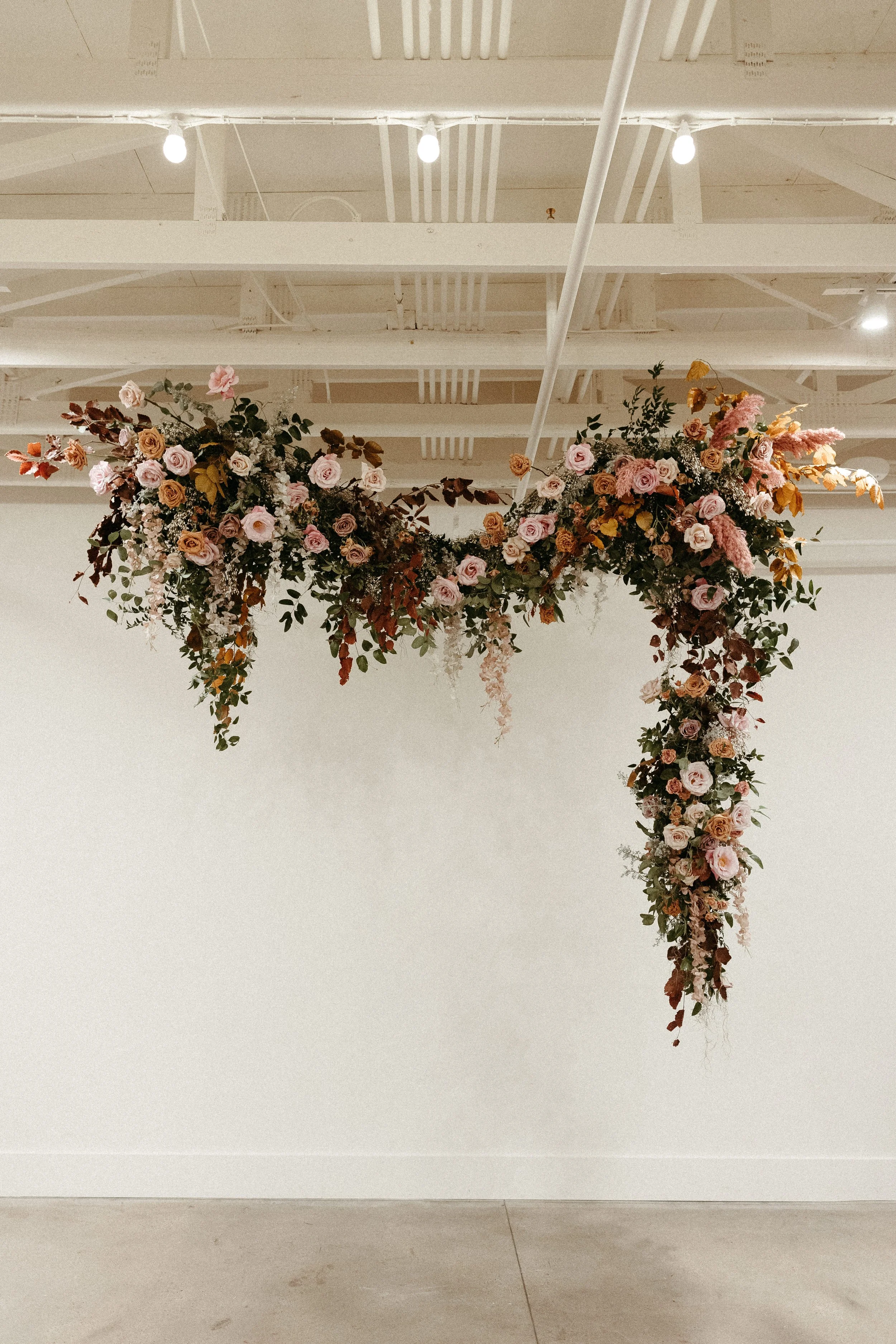 An eye-catching whimsical installation full of petal heavy roses and copper beech was the highlight of this art deco wedding. Terra cotta, burgundy, dusty pink, and other neutral florals warm up this ceremony. Designed by Rosemary and Finch in Nashvi