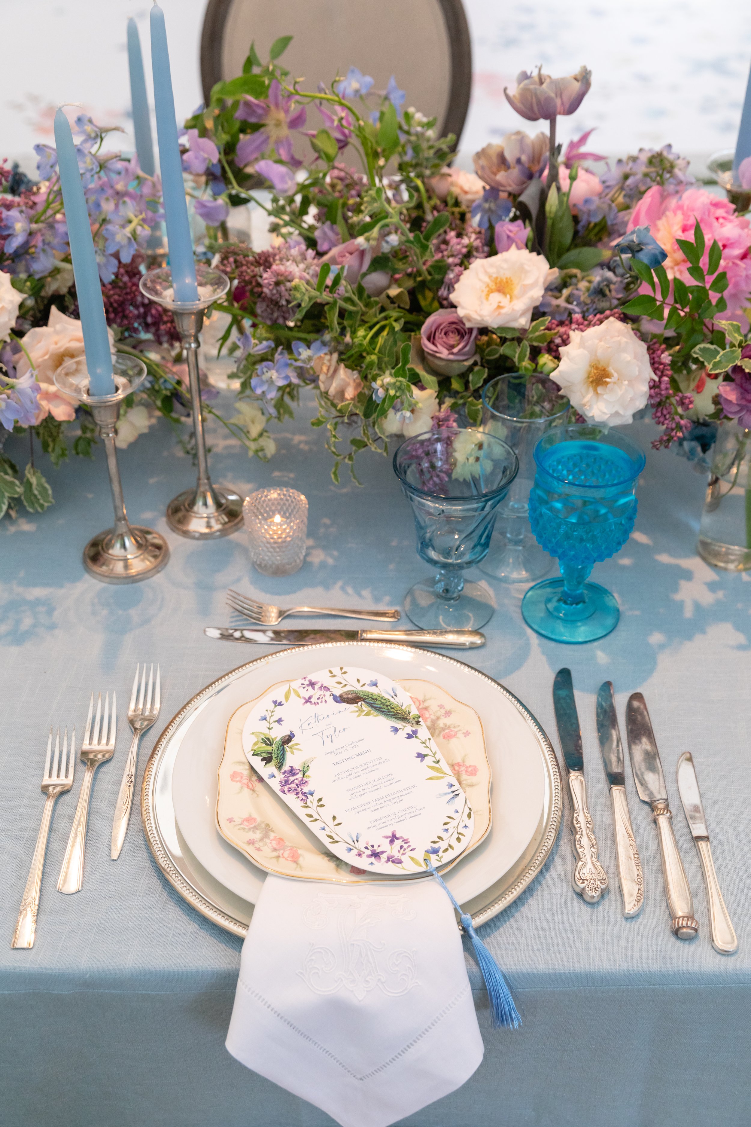 Growing, fresh floral centerpieces with blush garden roses, lilac, blue sweet peas, ranunculus, lavender delphinium, globe allium, clematis, and natural greenery for a tented Bridgerton inspired engagement party at a private home in Nashville, TN.