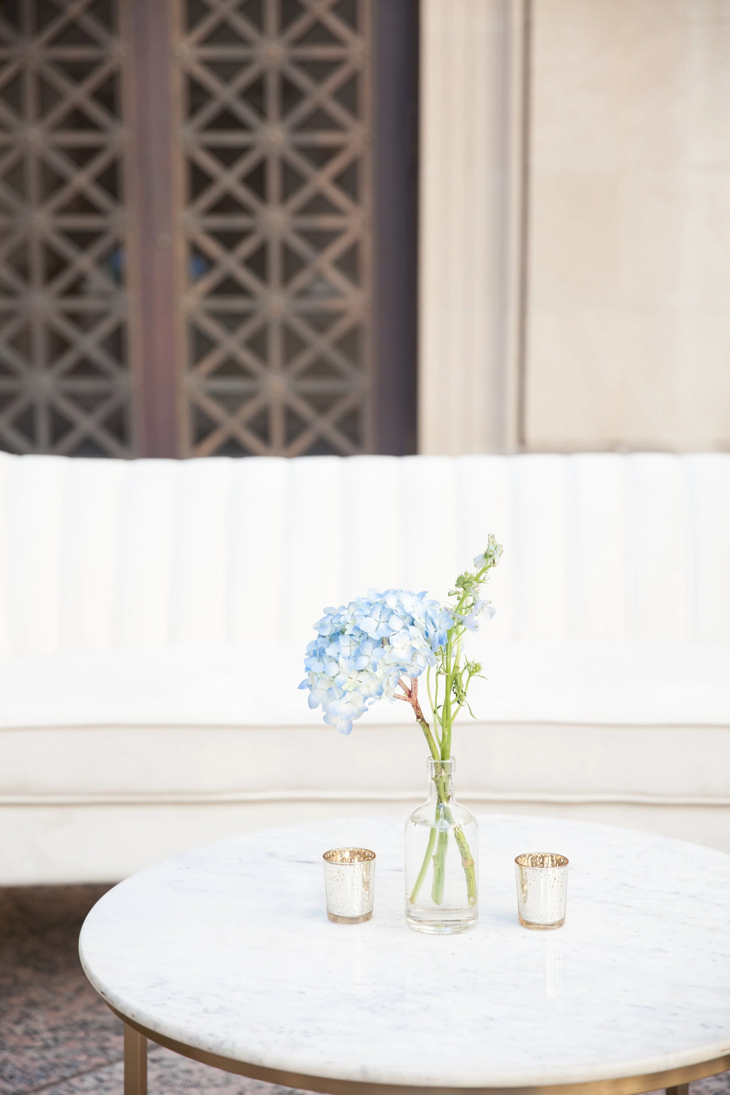 Bright dainty bud vases accent the welcome space of the War Memorial Auditorium in Nashville, TN. Following a color block theme comprised of hydrangeas, carnations, roses, and pampas grass. TPAC Gala designed by Rosemary and Finch.