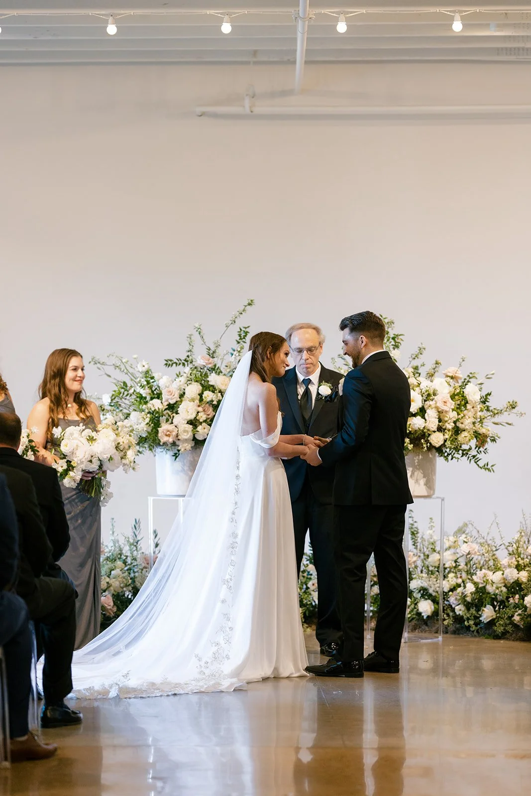 Lush ceremony installation featuring garden urns and meadows with petal heavy roses butterfly ranunculus, delphinium, and Queen Anne’s lace with natural, untamed greenery. Floral hues of white, cream, and blush. Designed by Rosemary and Finch in Nash