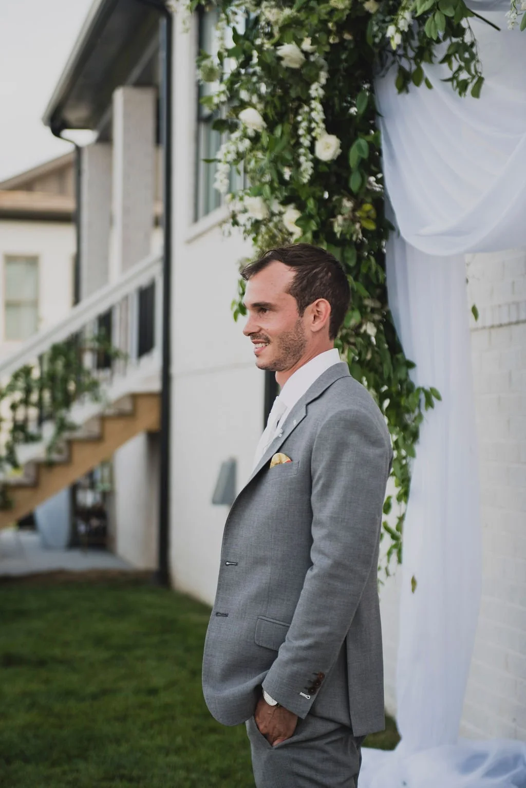 A ceremony backdrop arch overflowing with garden roses, white ranunculus, spray roses, delphinium, spirea, greenery and smilax vine. Designed by Rosemary and Finch in Nashville, TN.