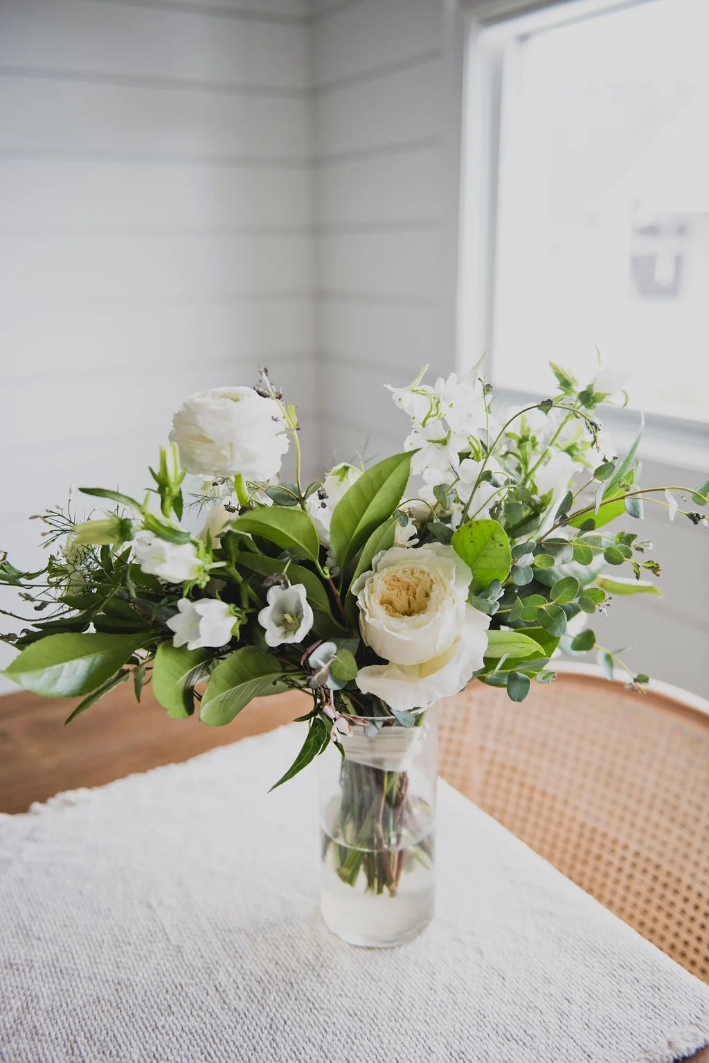 A bridal bouquet filled with ranunculus, delphinium, white sweet pea, spirea, garden roses, and jasmine vine. Designed by Rosemary and Finch in Nashville, TN.