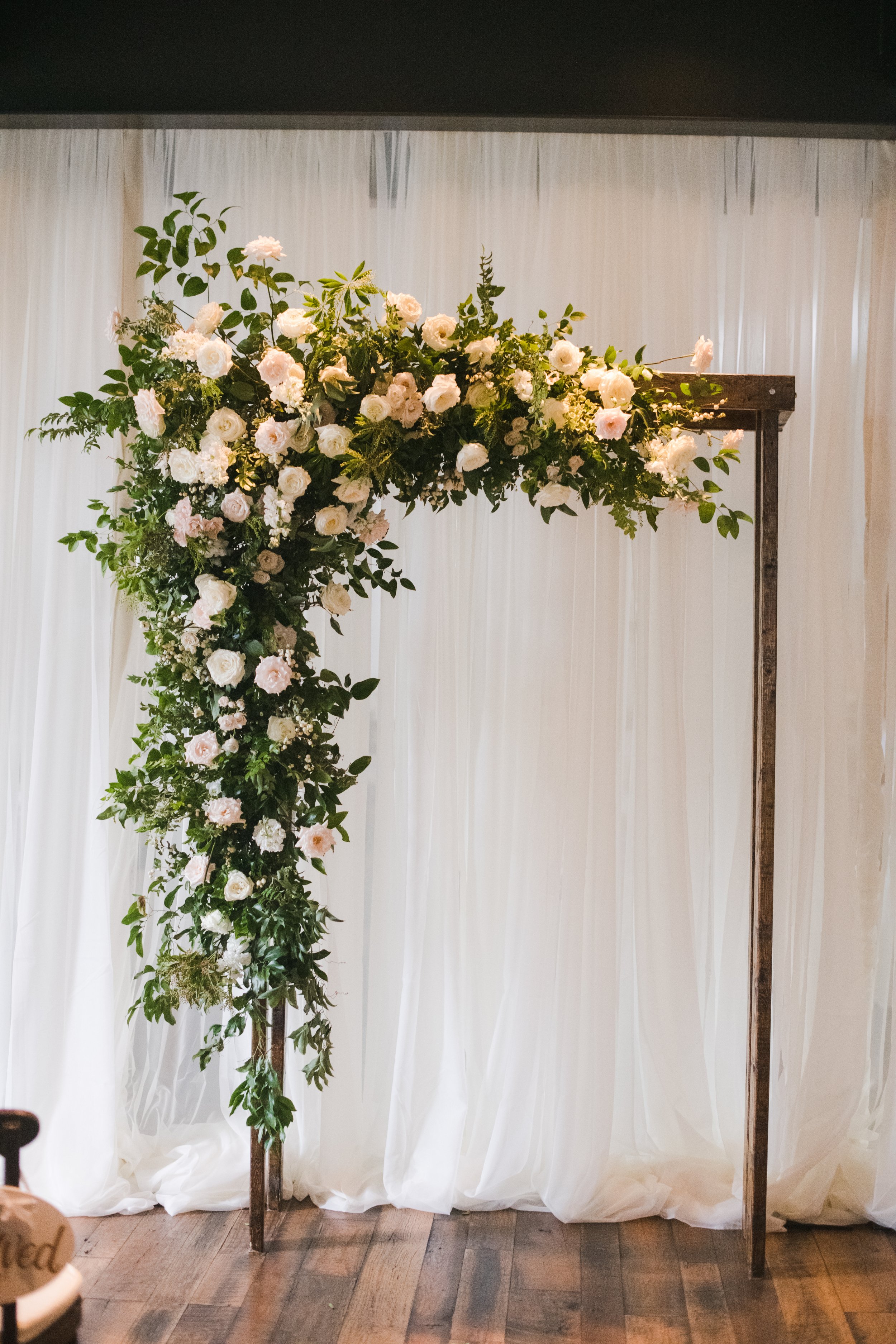 Lush ceremony arbor installation with all white garden roses and ranunculus with natural, untamed greenery. For garden-inspired wedding Designed by Rosemary and Finch in Nashville, TN.