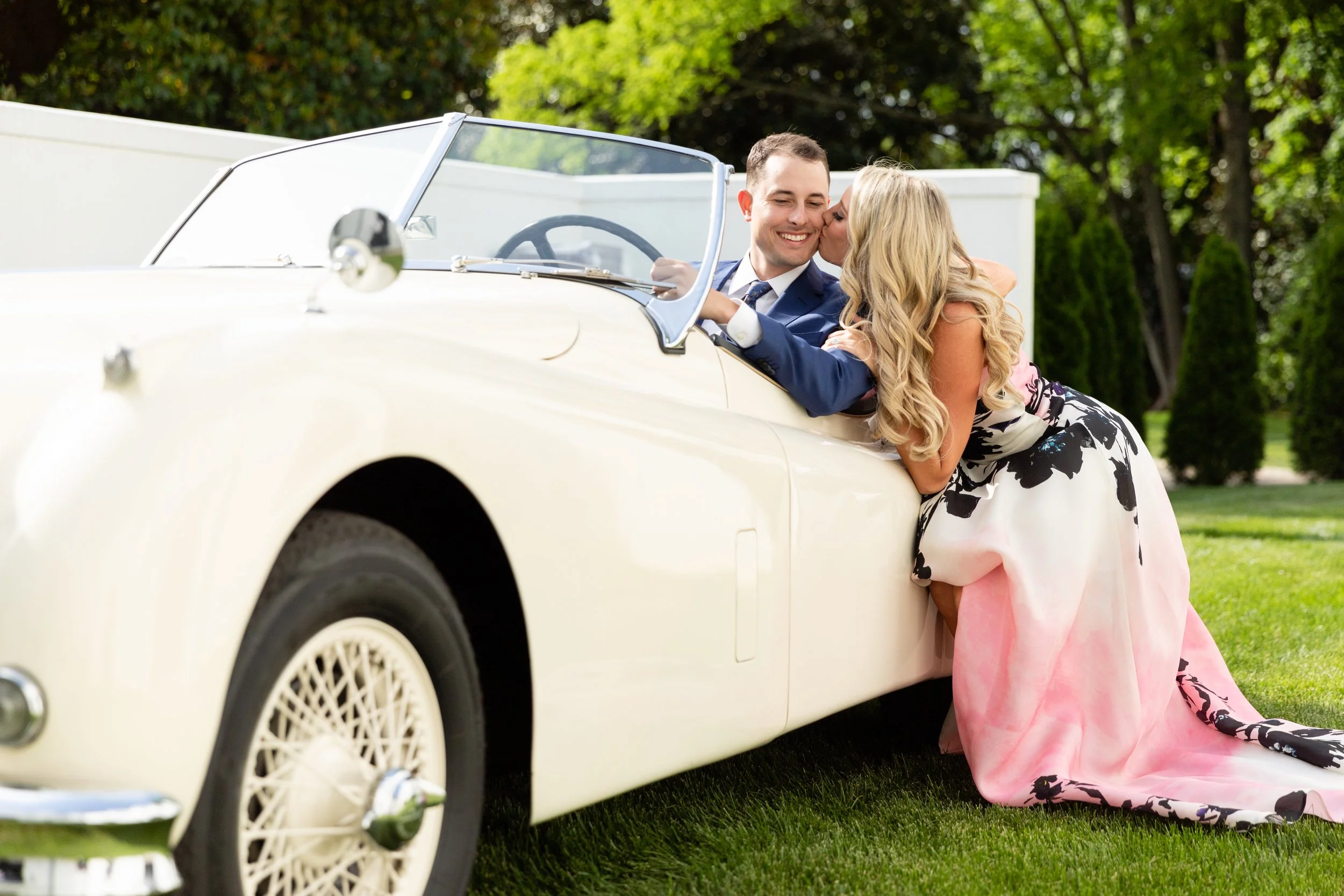 Bridgerton inspired engagement party at a private home in Nashville, TN with lush, organic floral installations of wisteria, spanish moss, and pastel blooms. Bride and groom portraits with a vintage Rolls Royce.