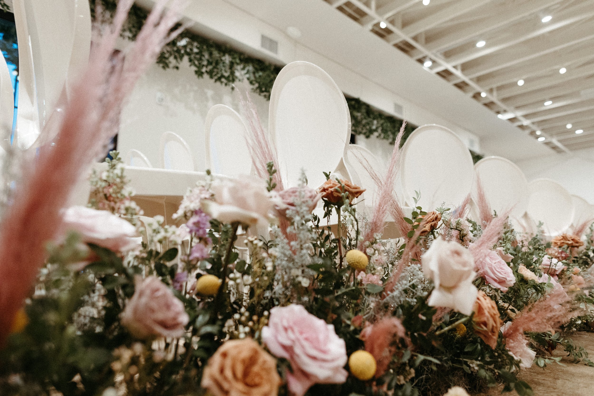 Lush aisle meadows beautifully frame the ceremony of this winter wedding with hues of dusty pink, terra cotta, cream, and sage green. Complete with petal heavy roses and pink pampas grass. Designed by Rosemary and Finch in Nashville, TN.