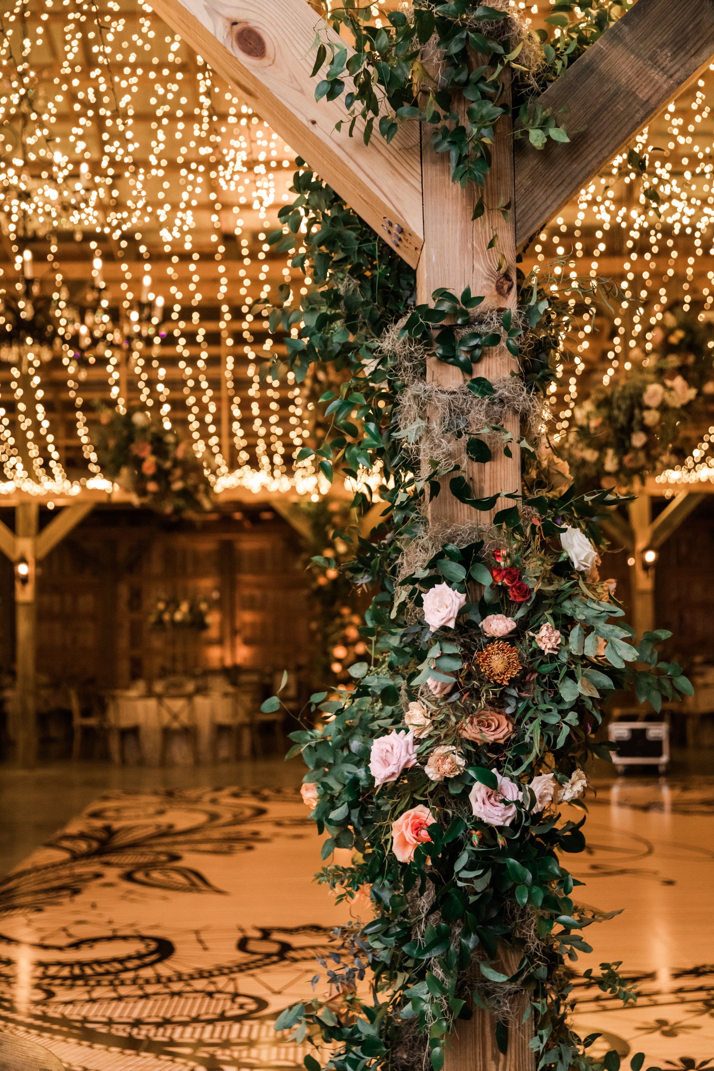 Climbing barn pole floral installations add pops of terra cotta, blush pink, and copper hues throughout the reception. Fall florals featuring garden roses and dahlias. Designed by Rosemary and Finch in Nashville, TN.