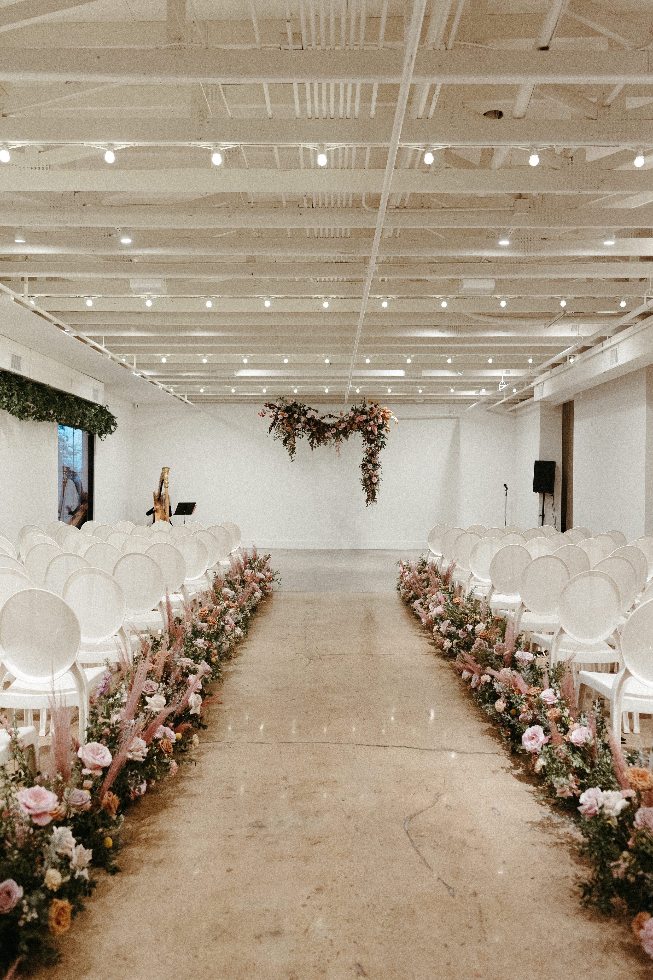 Lush aisle meadows beautifully frame the ceremony of this winter wedding with hues of dusty pink, terra cotta, cream, and sage green. Complete with petal heavy roses and pink pampas grass. Designed by Rosemary and Finch in Nashville, TN.