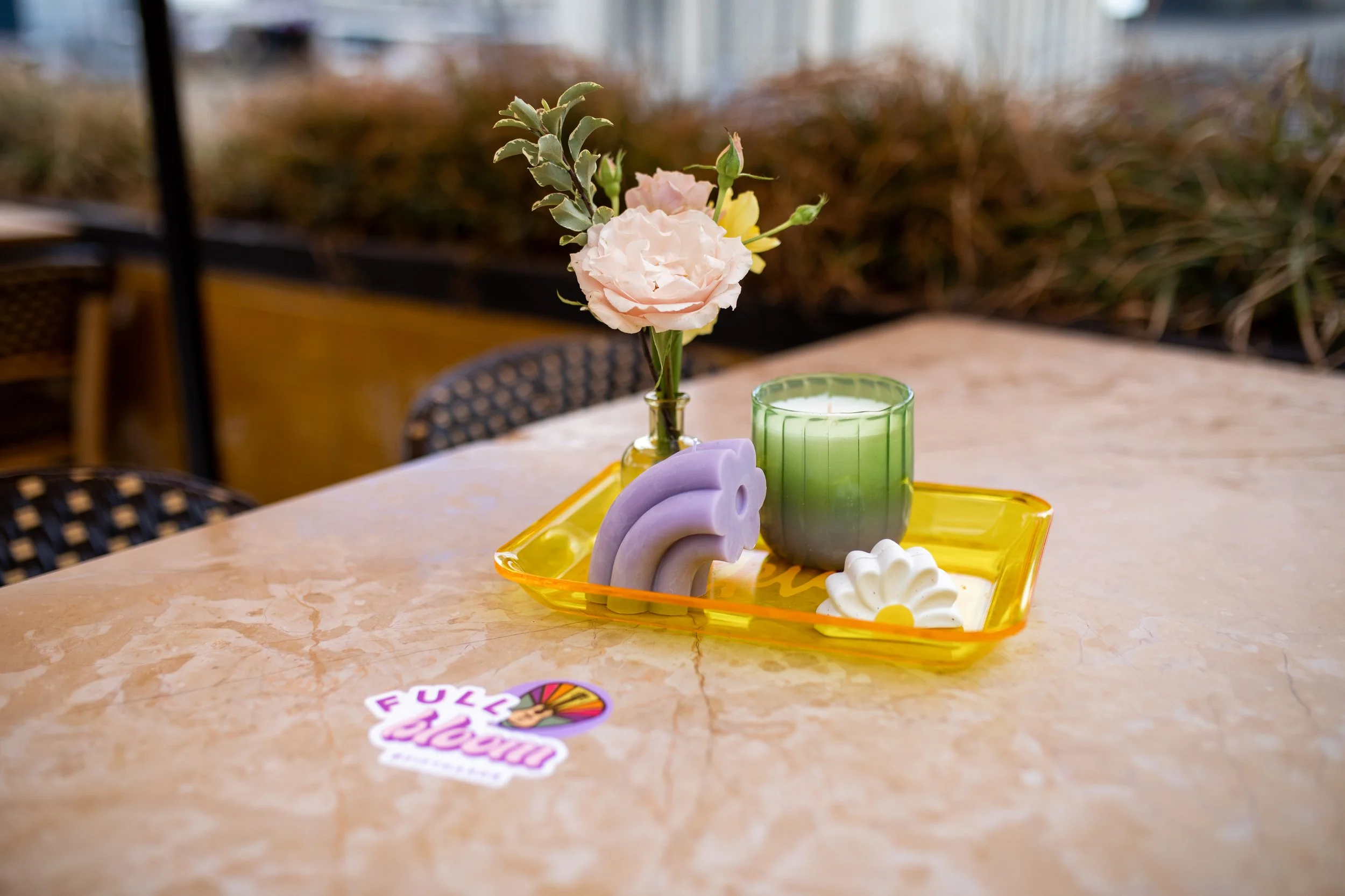 Dainty bud vases composed of roses, sweet peas, and ranunculus in floral hues of rich magenta, lavender, dusty pink, yellow, and mixed greenery. Paired with candles of unique shapes and hues. Design for Fifth + Broadway Spring by Rosemary and Finch.