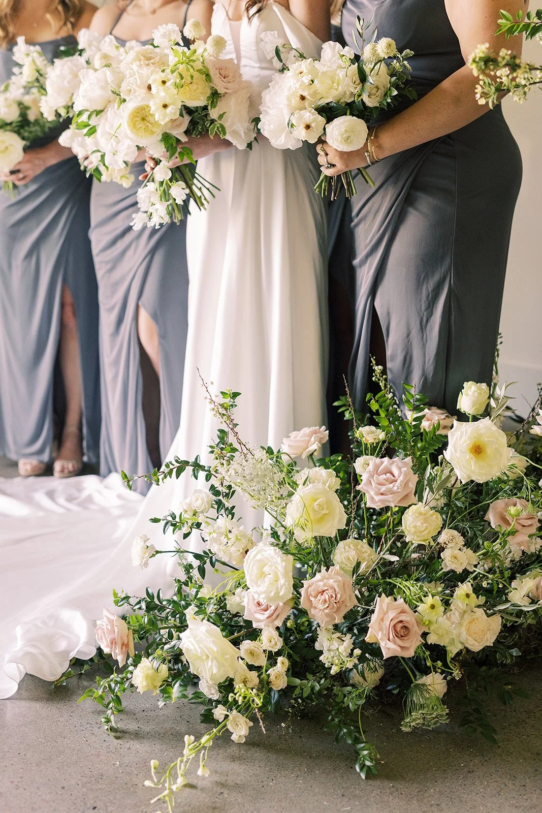 Bridal party florals of white garden roses, peonies, ranunculus, sweet peas, scabiosa, butterfly ranunculus and dark greenery in floral hues of white, cream, and blush. Designed by Rosemary and Finch in Nashville, TN.