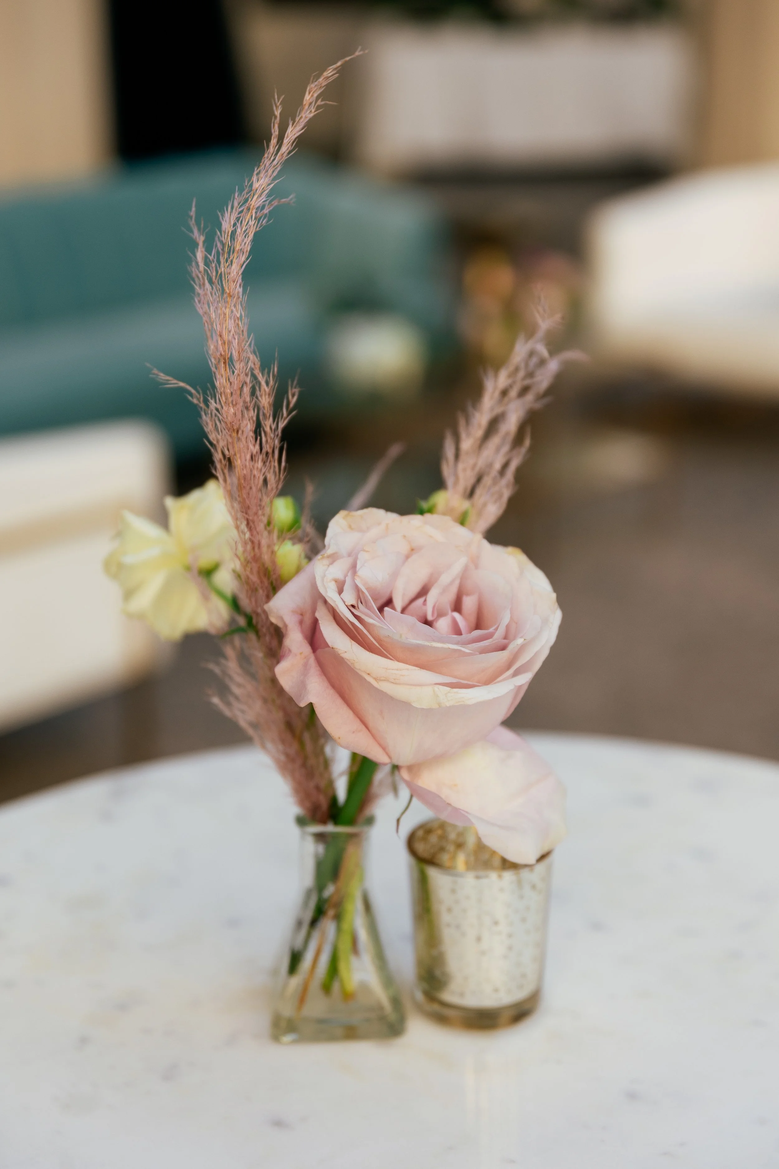 Bright dainty bud vases accent the welcome space of the War Memorial Auditorium in Nashville, TN. Following a color block theme comprised of hydrangeas, carnations, roses, and pampas grass. TPAC Gala designed by Rosemary and Finch.