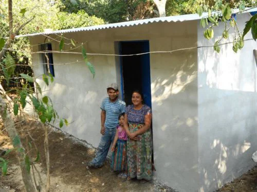 The family stands in the doorway of their newly built house.