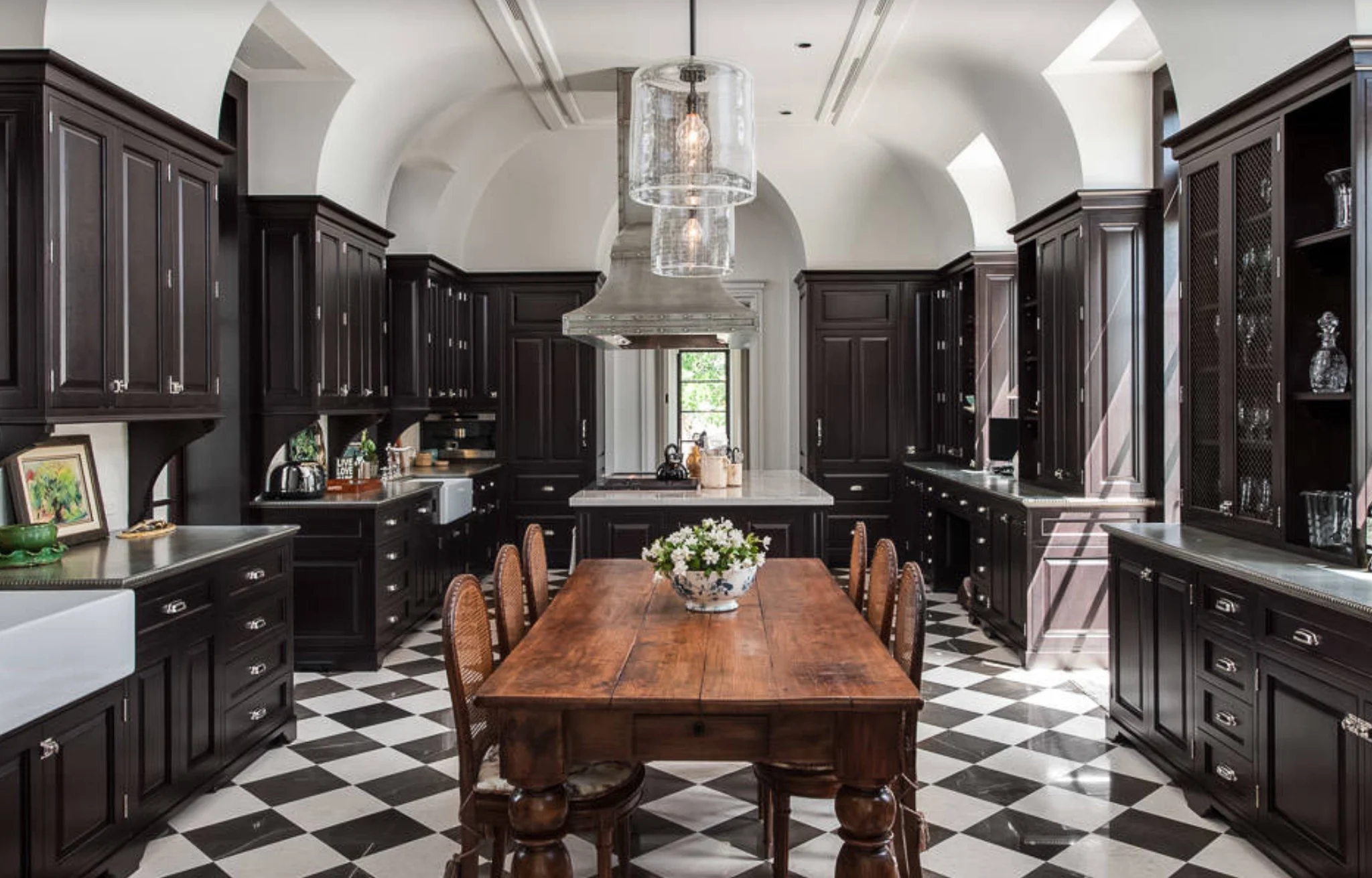 Black cabinetry with checkerboard floor and antique farmhouse table - Design by Alonso and Associates