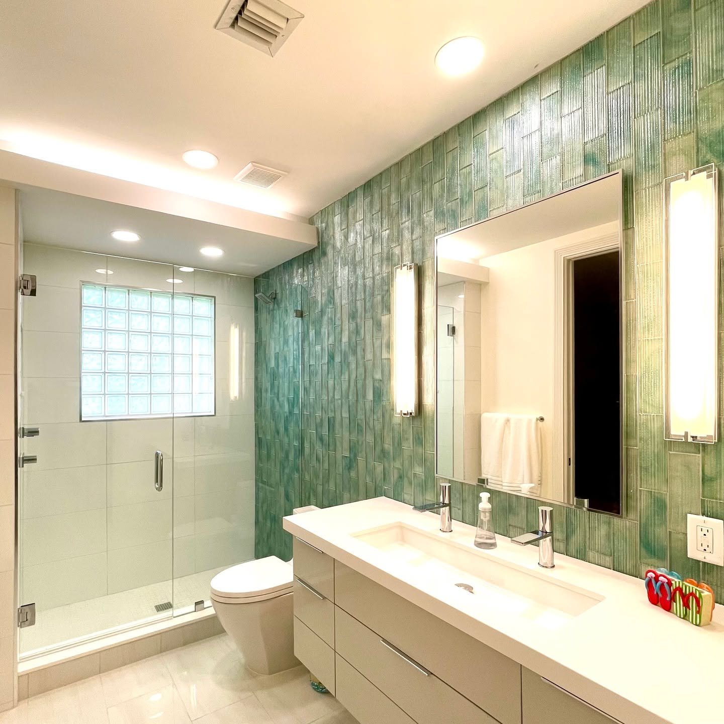 Using tile to make an impact in a guest bathroom - it's the thing to do! Love this @oceansideglasstile and how it sets the tone. A double wide sink with two faucets is a good alternative to double sinks (plus, it helps gain important storage!). Thank