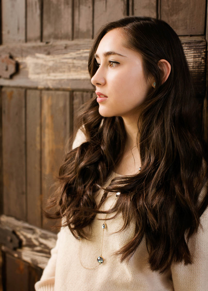  High school senior photography of a young woman against a rustic wood background by Campbell Salgado Studio. 