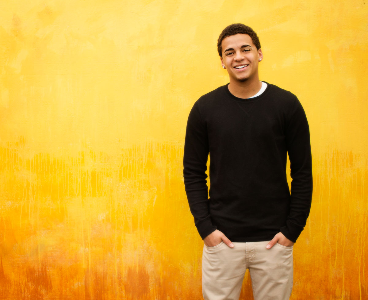 High school senior photography of a young man standing in front of a yellow background, photographed by the Portland high school senior photographers at Campbell Salgado Studio in Portland, Oregon 