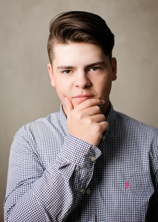  High school senior pictures of a young man against a gray background by Campbell Salgado Seniors. 