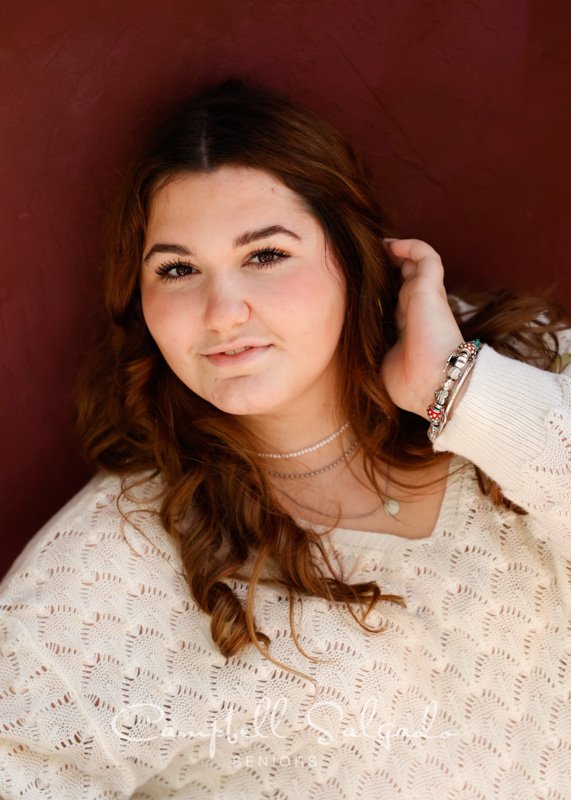  Senior picture of a young woman on a plum stucco background by high school senior photographers at Campbell Salgado Studio in Portland, Oregon. 