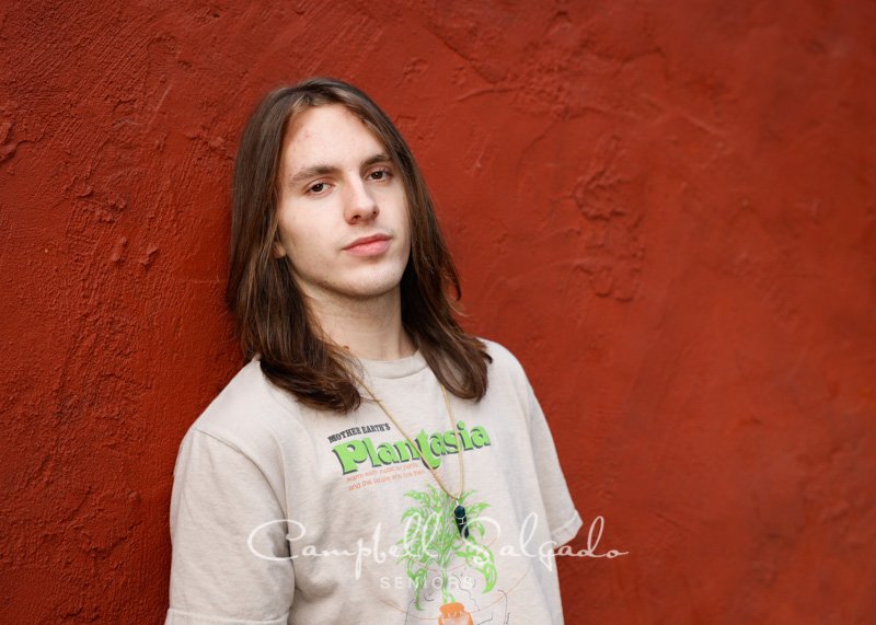  Portrait of young man against a red stucco background by Portland photographers - senior pictures at Campbell Salgado Studio in Portland, Oregon. 