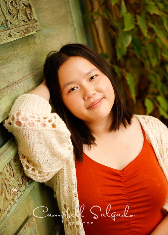  High school senior portraits of a young woman in front of a vintage green doors background by senior photographers at Campbell Salgado Studio in Portland, Oregon. 