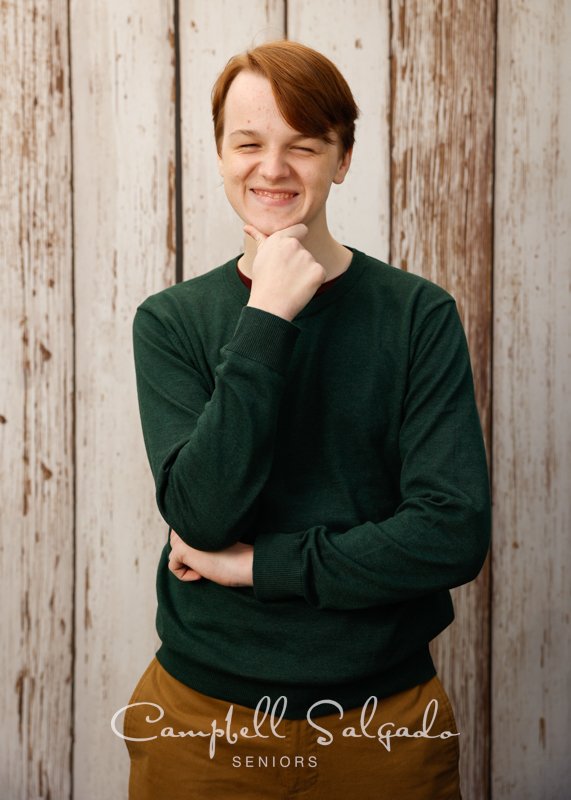  Senior photos, Portland Oregon of young man in front of a white fenceboards background by photographers at Campbell Salgado Studio. 