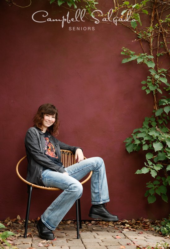  Portrait of young woman against a plum stucco background by Portland senior picture photographer Kim Campbell of Campbell Salgado Studio in Portland, Oregon. 