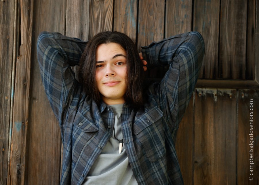  Senior picture of a young man on barn doors background by high school senior portrait photographer at Campbell Salgado Studio in Portland, Oregon. 