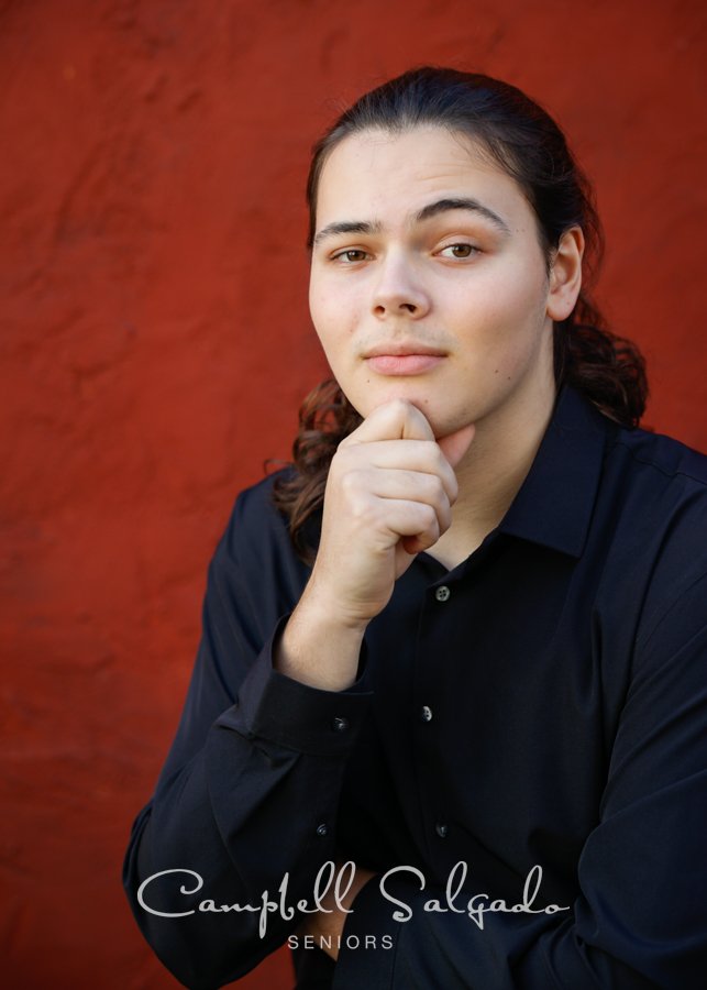  Professional senior portraits of young man&nbsp;in front of a red stucco background by Portland, Oregon photographers at Campbell Salgado Studio. 