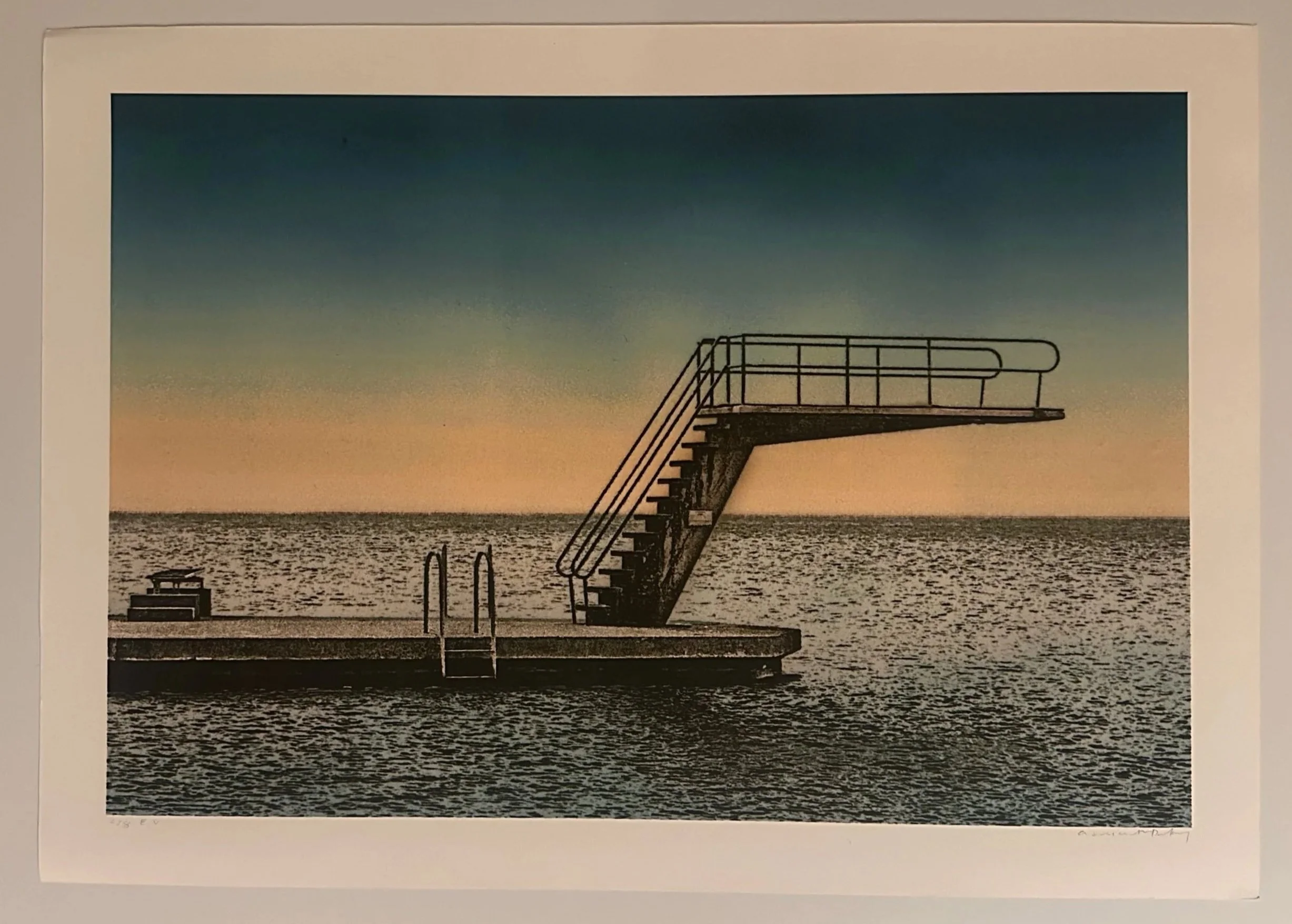 A sunset view at a beach with a diving board extending over the water, the sky transitioning from blue to warm tones, with some clouds.