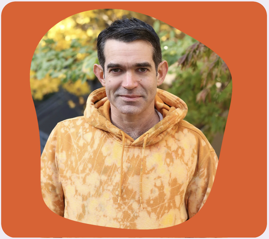 Dan Costello outside standing in front of a colorful tree in the fall.