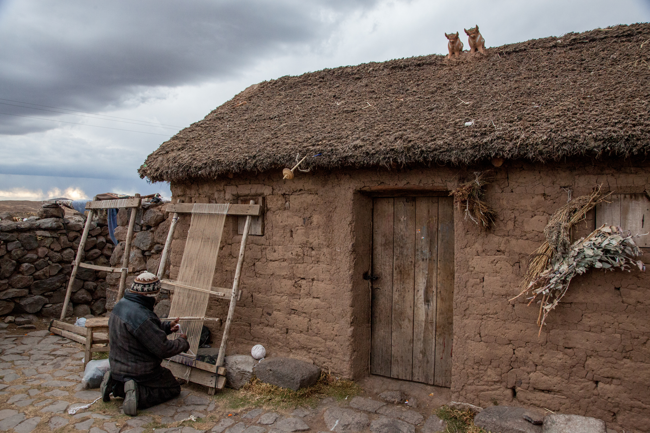 Weaver near Sillustani. Note the toritos, or little bulls, on the rooftop. They are a very common decoration in the altiplano, even up into Cusco.