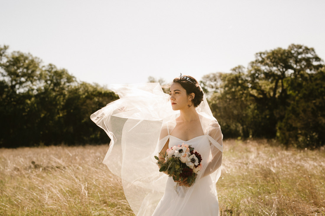 Bride with veil in the wind in hill country forest.
