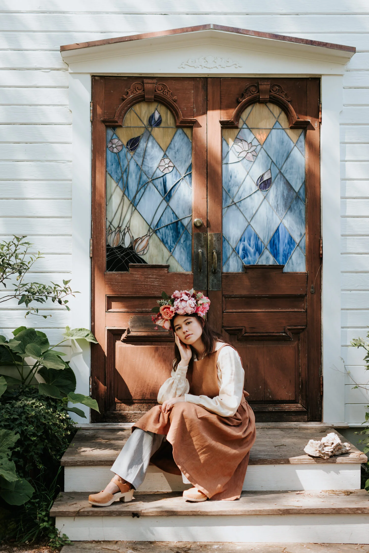 Model in flower crown and vintage clothing in front of stained glass