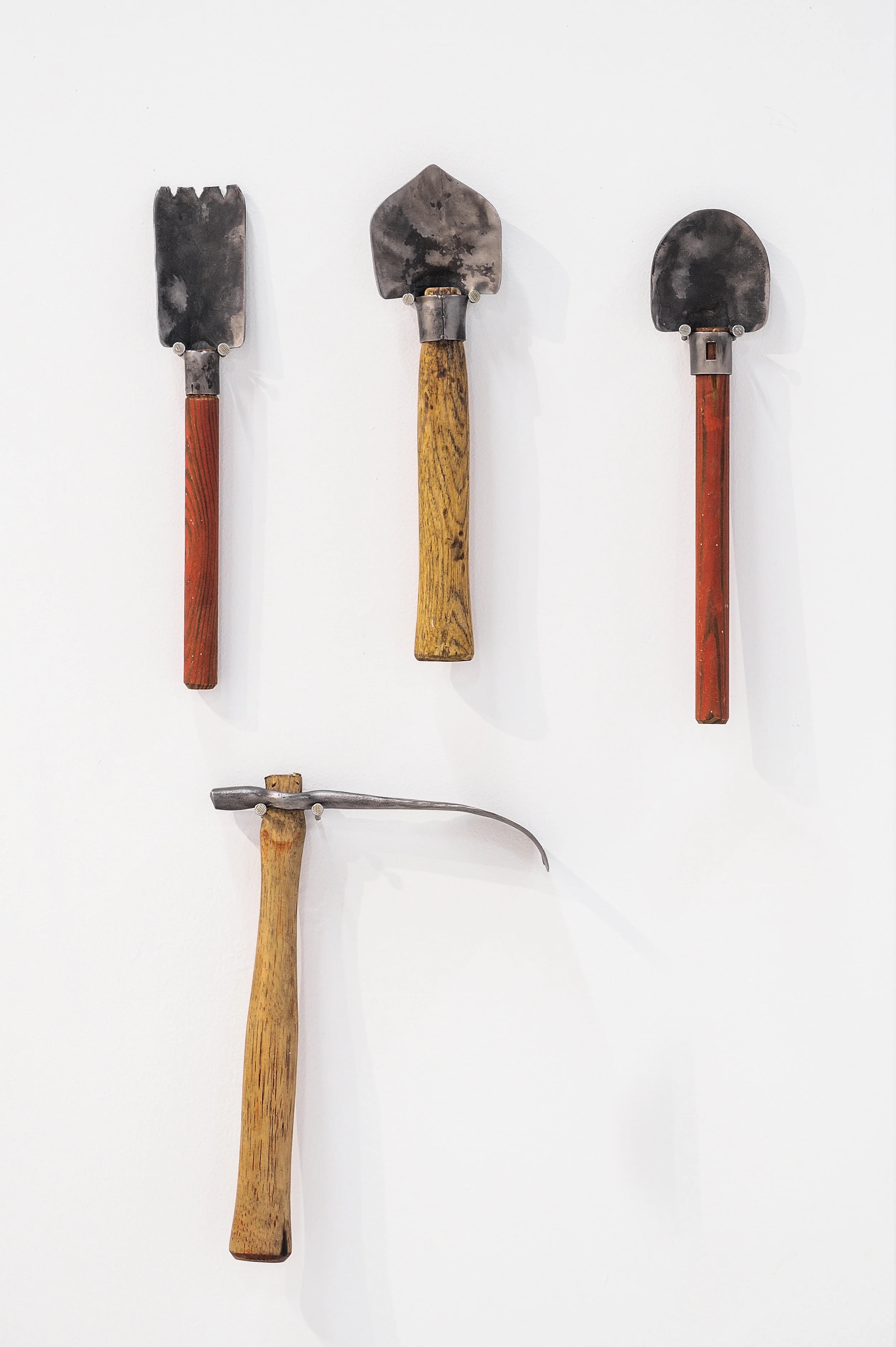 Trowel I , 2019, forged gun barrels, wood, 13” x 2.25” x 1” Trowel II , 2019, forged gun barrels, wood, 13” x 3” x 1” Trowel III , 2019, forged gun barrels, wood, 12.5” x 3.25” x 1” Adz I , 2018, forged gun barrels, wood, 12.375” x 8.875” x 2”